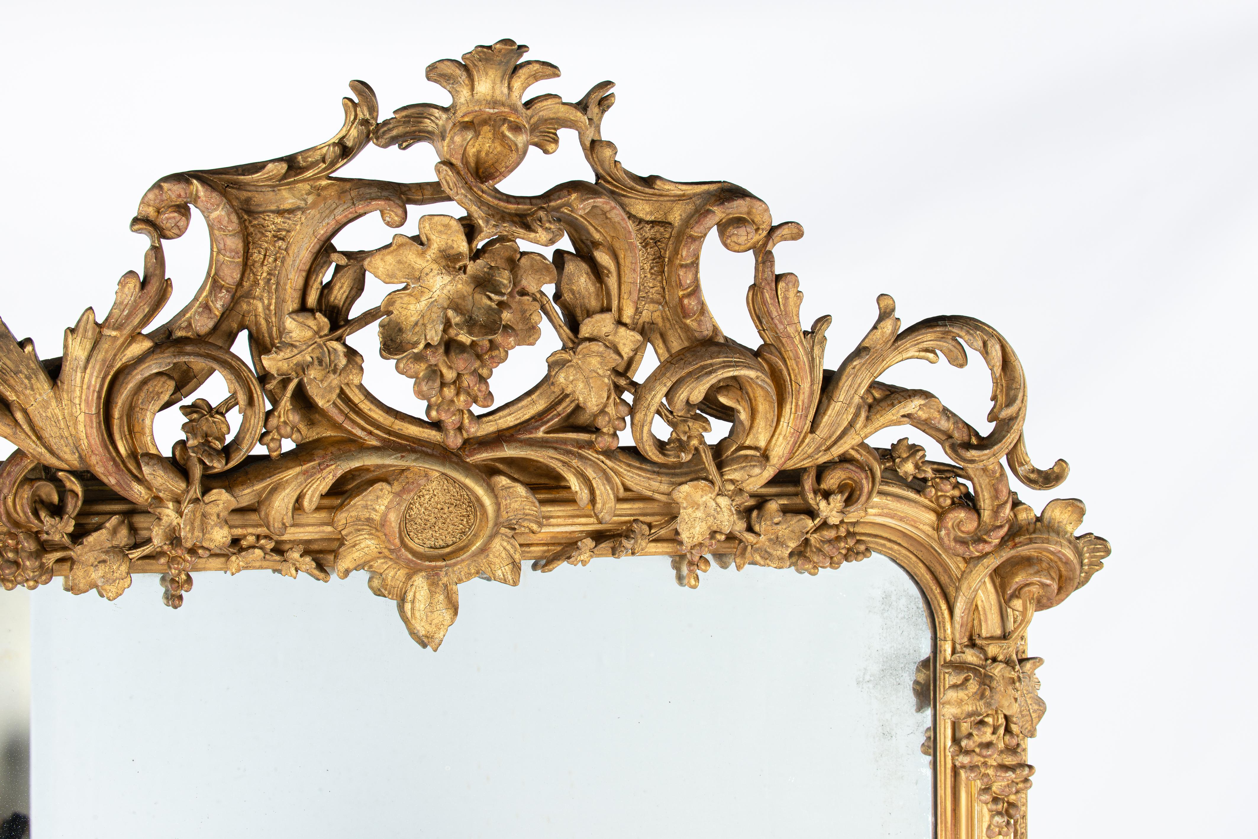 Dieser monumentale und reich verzierte Spiegel wurde zu Beginn des 19. Jahrhunderts, um 1830, in Südfrankreich hergestellt. Der Spiegelrahmen weist die für den Louis-Philippe-Stil typischen abgerundeten oberen Ecken auf. Die außerordentlich üppige