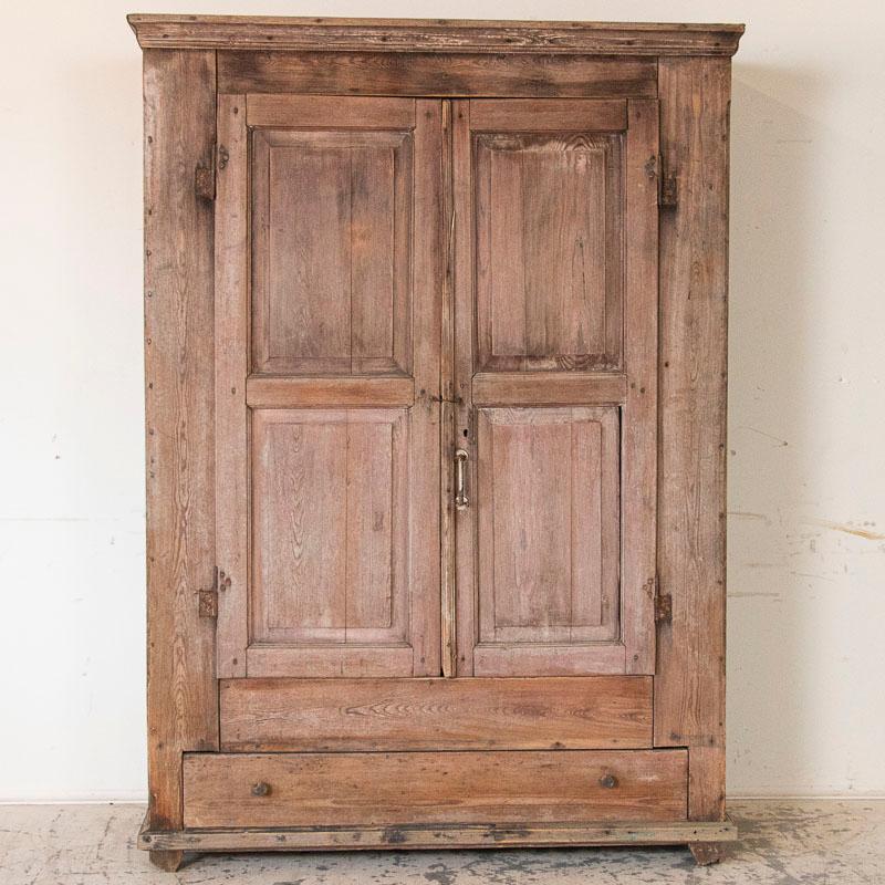 This large armoire has loads of character reflected in the aged wood itself. Notice the texture of the gently sanded weathered wood, inviting you to run your hand along the grain. Open the two doors and you will find to the left 9 upper hooks as