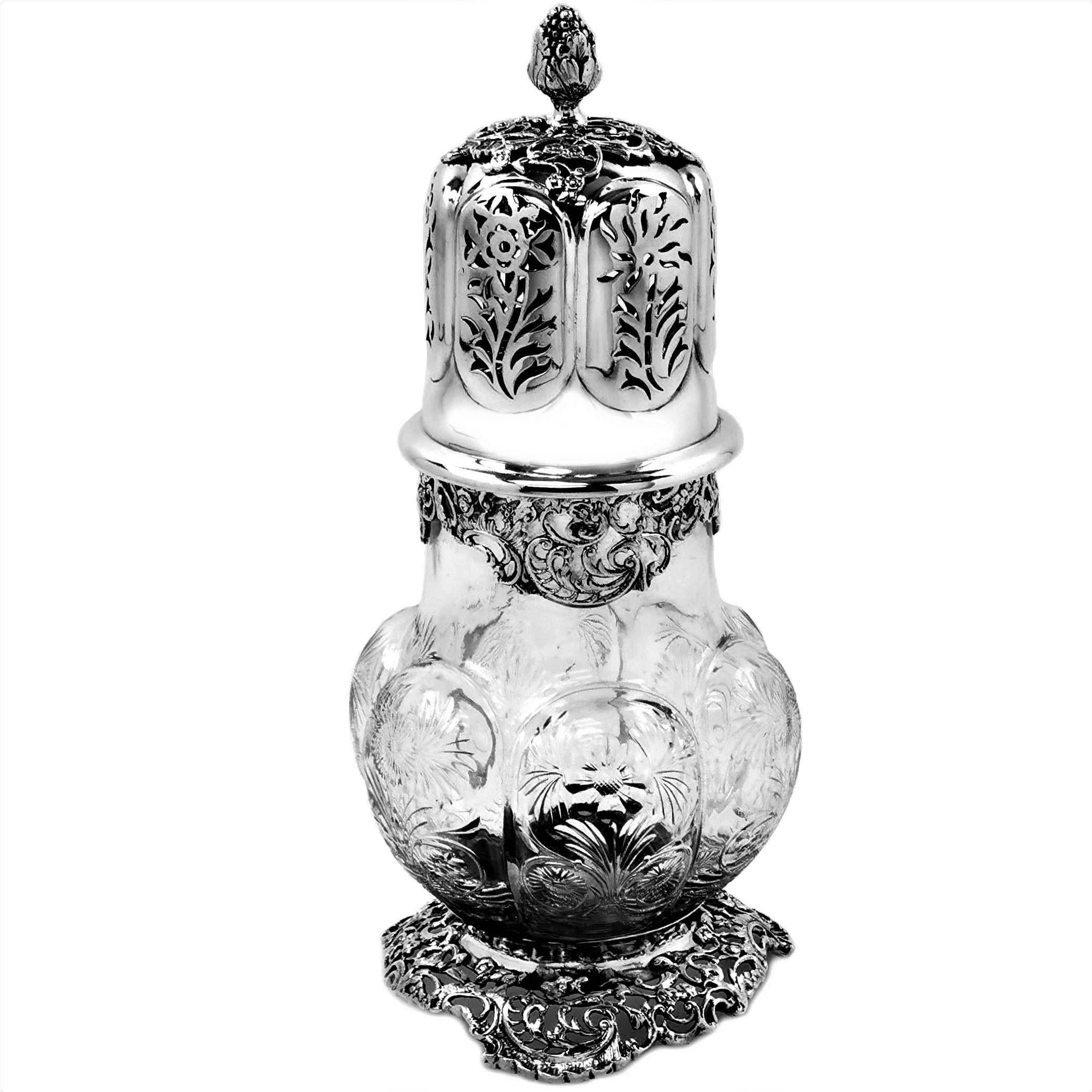 A beautiful Antique Edwardian Silver Mounted and Glass Caster. The Cut Glass body of the Caster features detailed floral images on each of the lobed panels. The Caster stands on a three sided pieces and chased foot , the patterns of which are