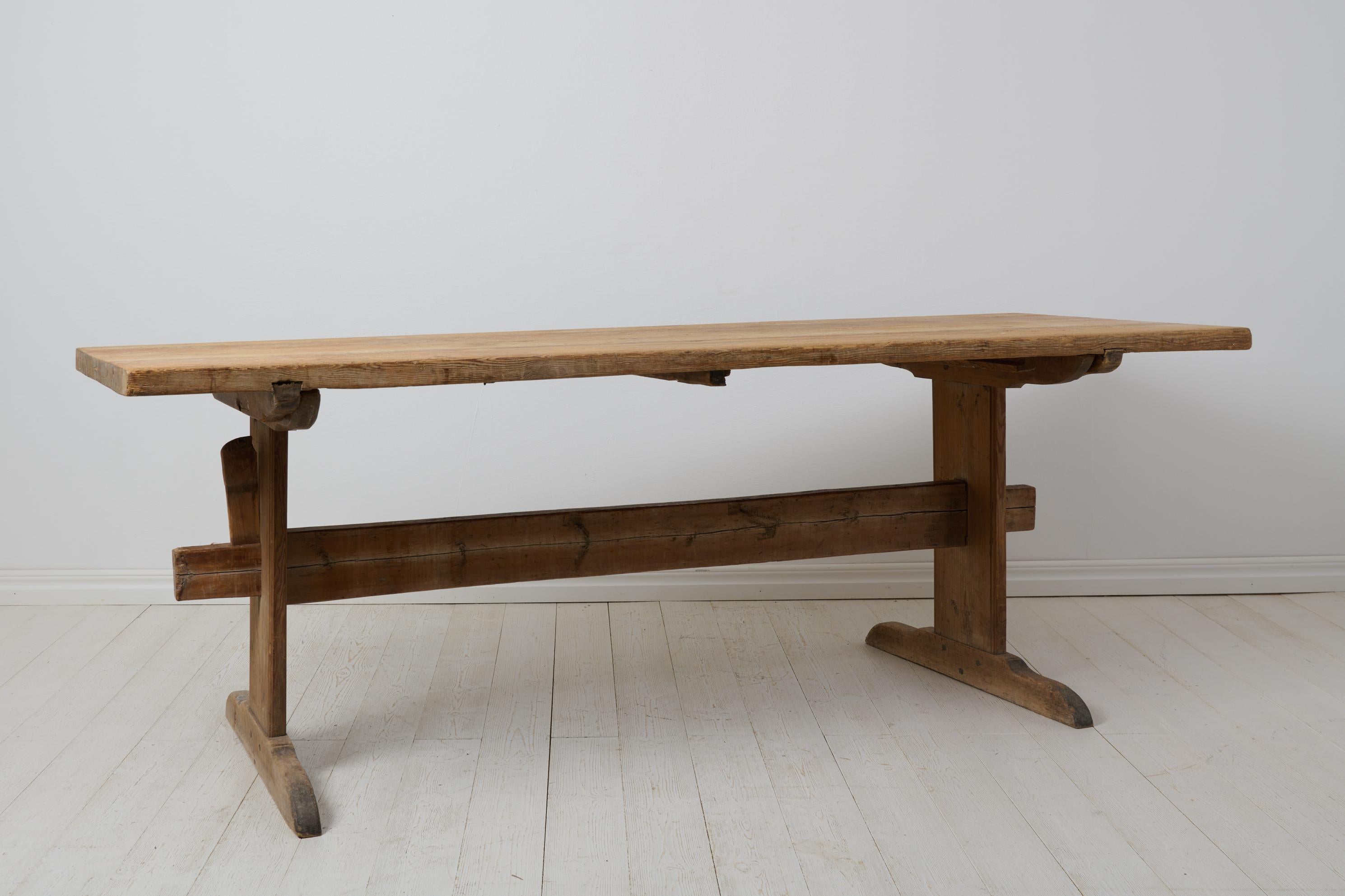 Large trestle dining table from northern Sweden. The table is a genuine antique made by hand in pine around 1820 to 1840. The table top is solid wood made of only two boards. The wood has never been painted and has a genuine patina after 200 years