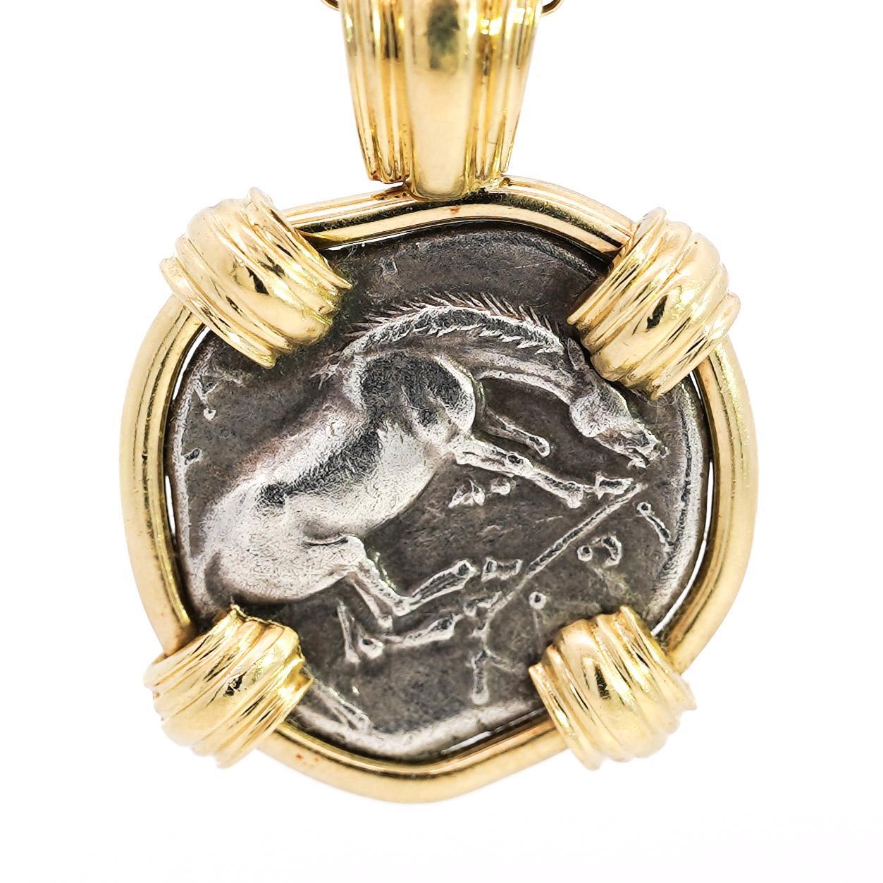 This stunning 18K yellow gold pendant features an ancient Larissa Greek coin. The coin is intricately displayed within a secure bezel, highlighting its rich historical design. A perfect statement piece for collectors or those seeking unique,