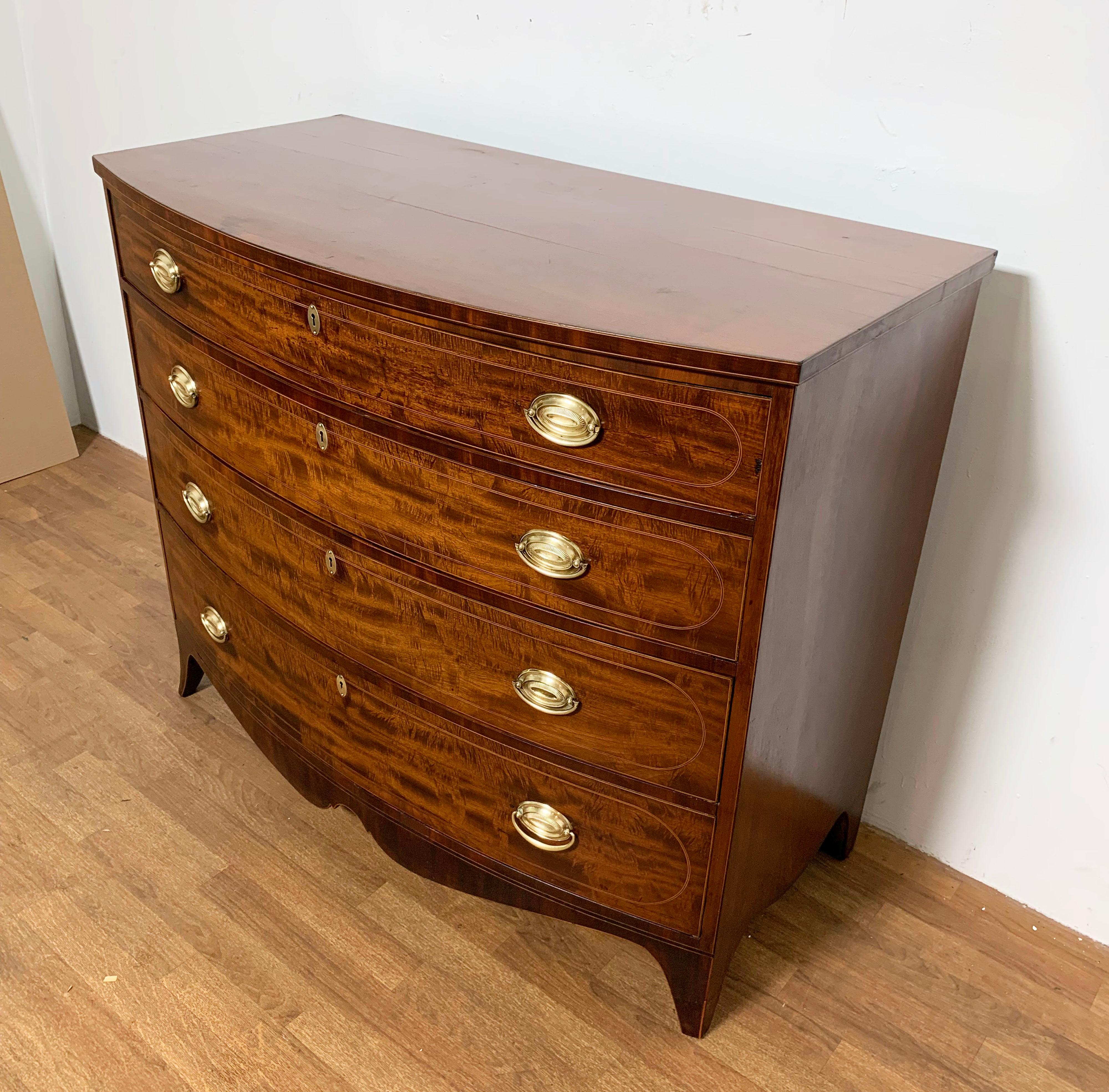 A fine and generously proportioned antique Federal bow front chest of flame mahogany with string banding and French feet, ca. 1790.