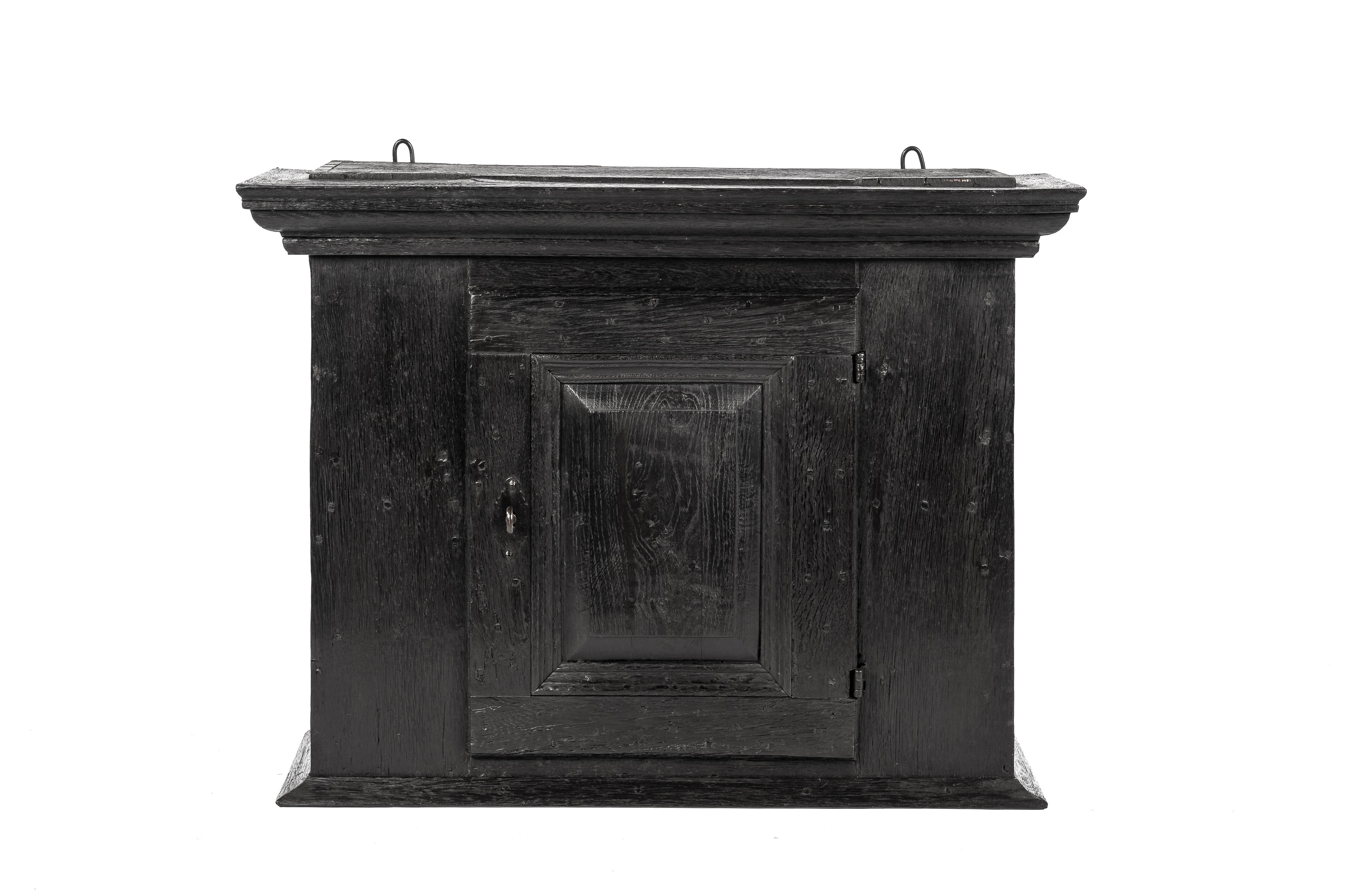 This is a beautiful wall-hanging cabinet that was made in Germany in the late 18th century. It was completely made in solid European oak and stained almost black. The cabinet has its original forged steel hinges and keyplate. Its lock and key were