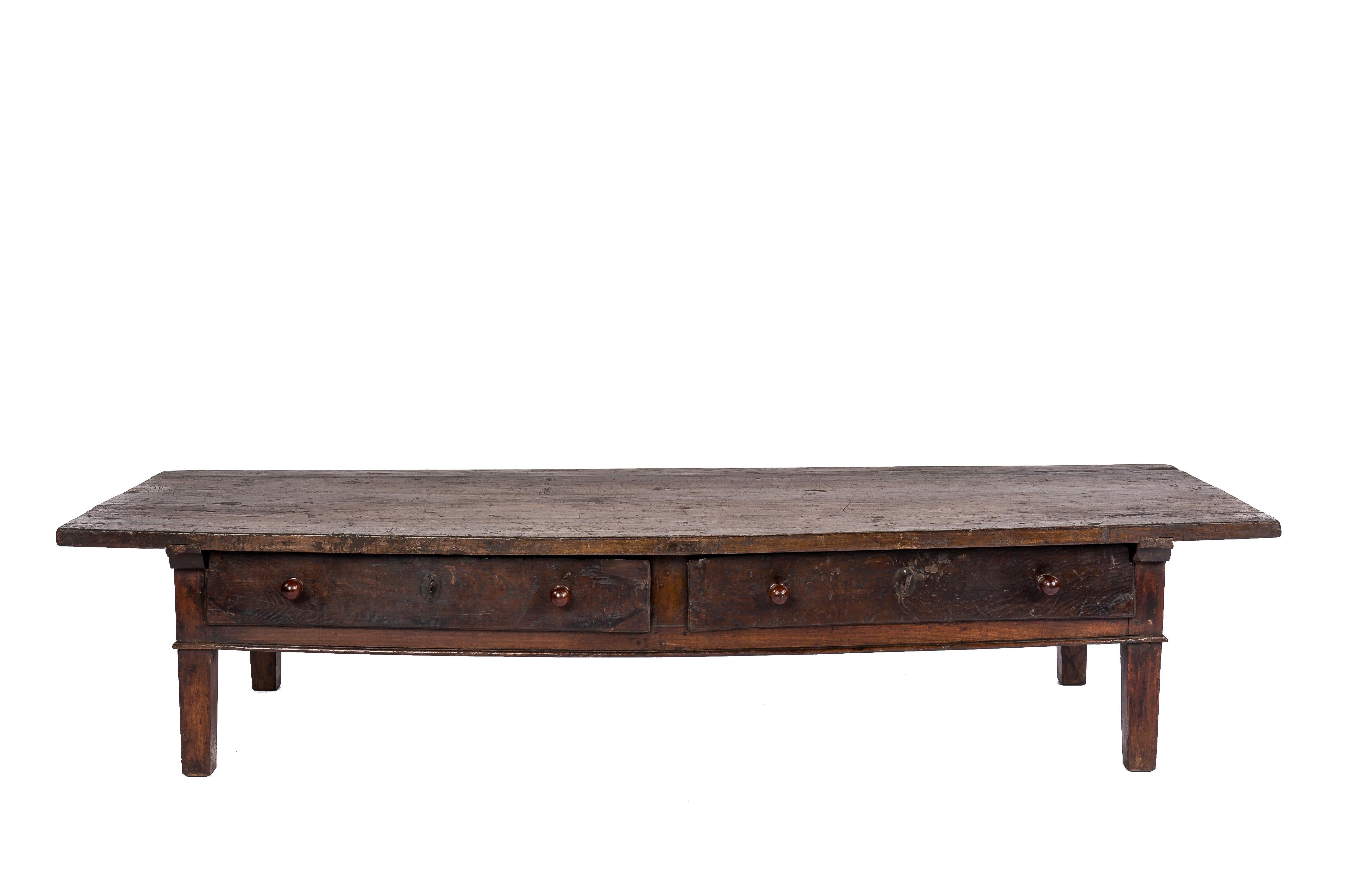 This beautiful warm brown color rustic coffee table or low table originates in rural Spain and dates circa 1770. The table is exceptionally long and has a unique top that was made from a very wide and narrow board of solid chestnut wood that is 1.4