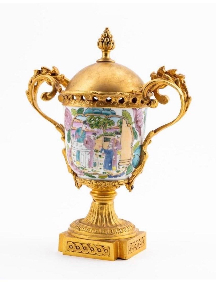Chinese. Bronze dore mounted porcelain cup with gilt brass top, having a hand painted figural court scene with floral decoration. Apparently unmarked.