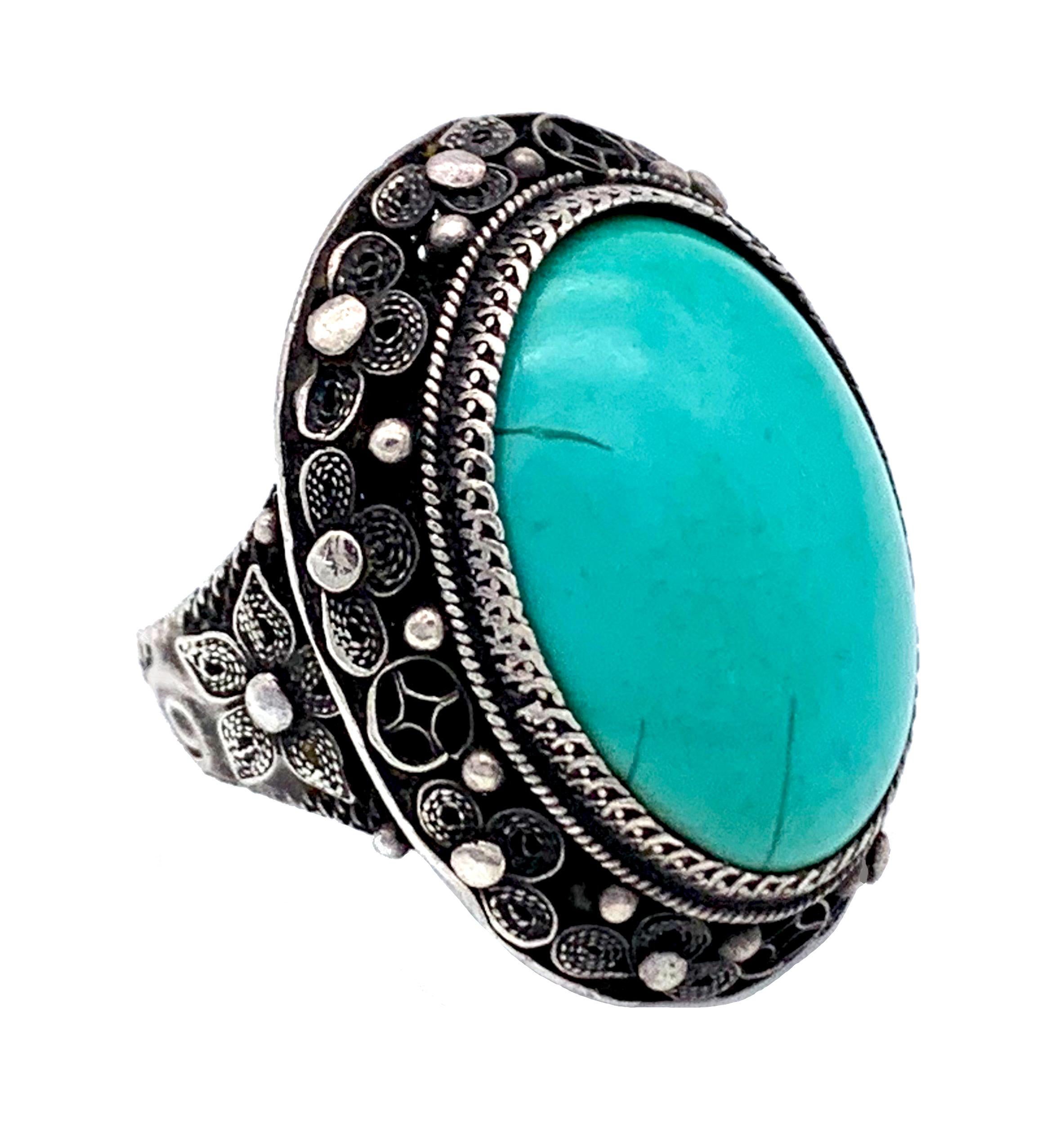 Cette magnifique bague chinoise en argent de la fin du XIXe siècle est sertie d'un cabochon de turquoise merveilleusement brillant.
La fine monture est décorée d'un travail de fil et de granulation complexe.

Le haut de l'anneau mesure 2,7 x 2,2 cm