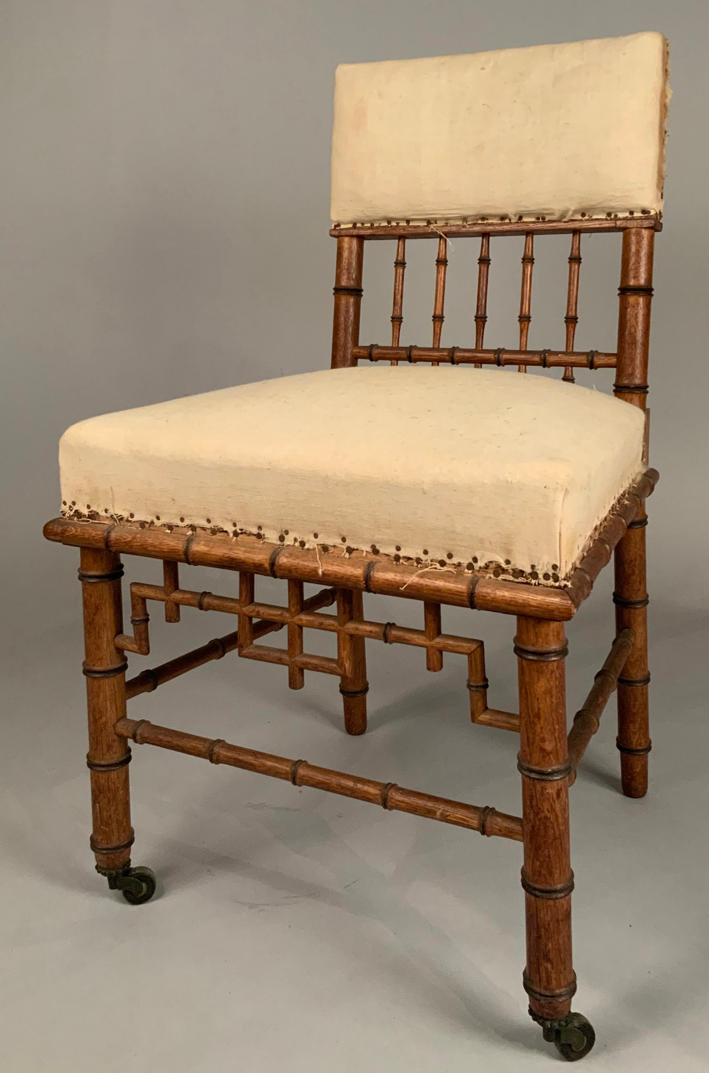 A very charming antique 19th century English side chair, in bamboo form, with chippendale details. the chair has an upholstered and vertical rail back, a bamboo ledge below the seat and casters on the front legs. beautiful scale and details. the
