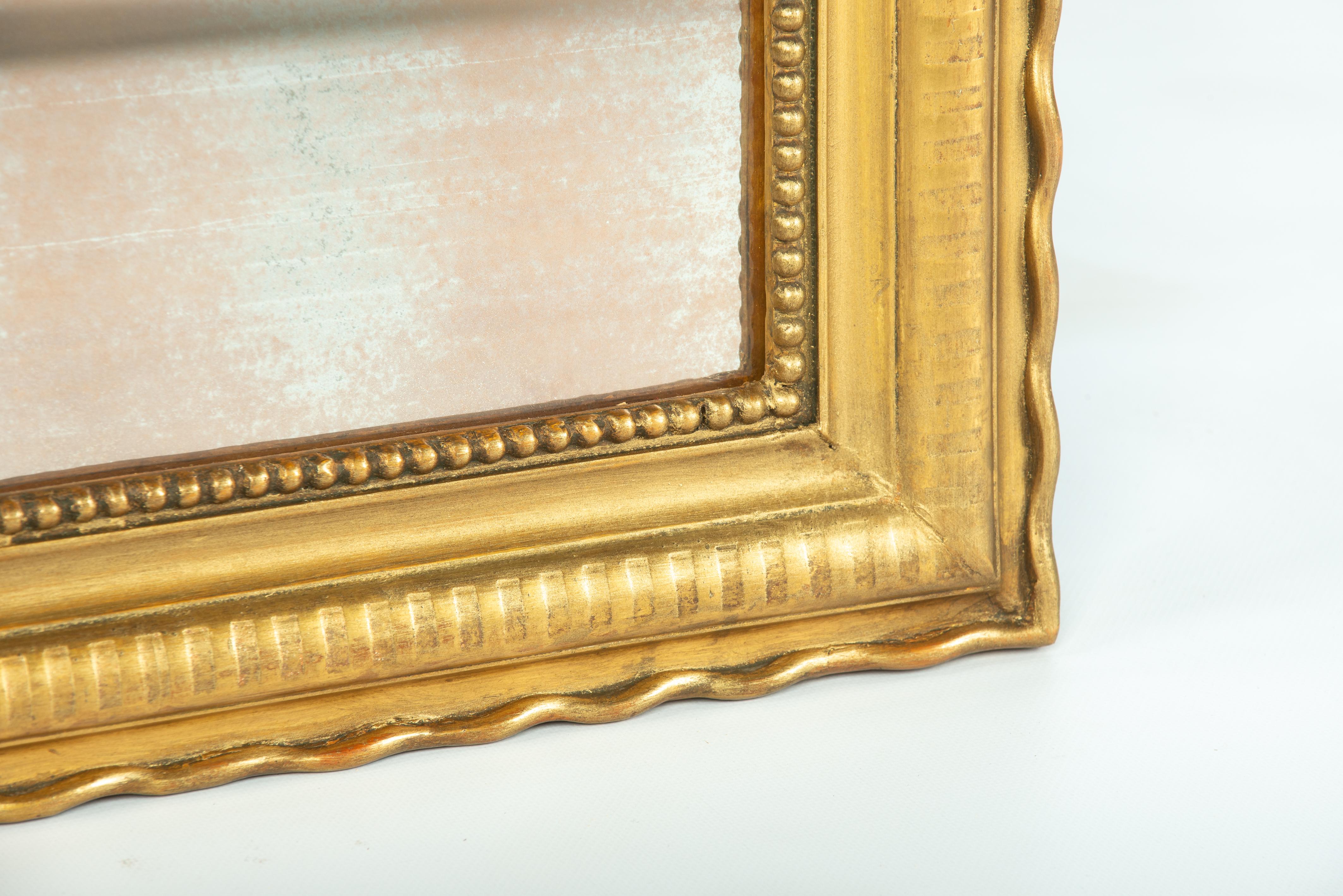 Offered here is a beautiful antique gold leaf-gilded Louis Philippe mirror from France. This mirror dates back to around 1870 and features rounded upper corners characteristic of the Louis Philippe style. Crafted in the south of France, it is