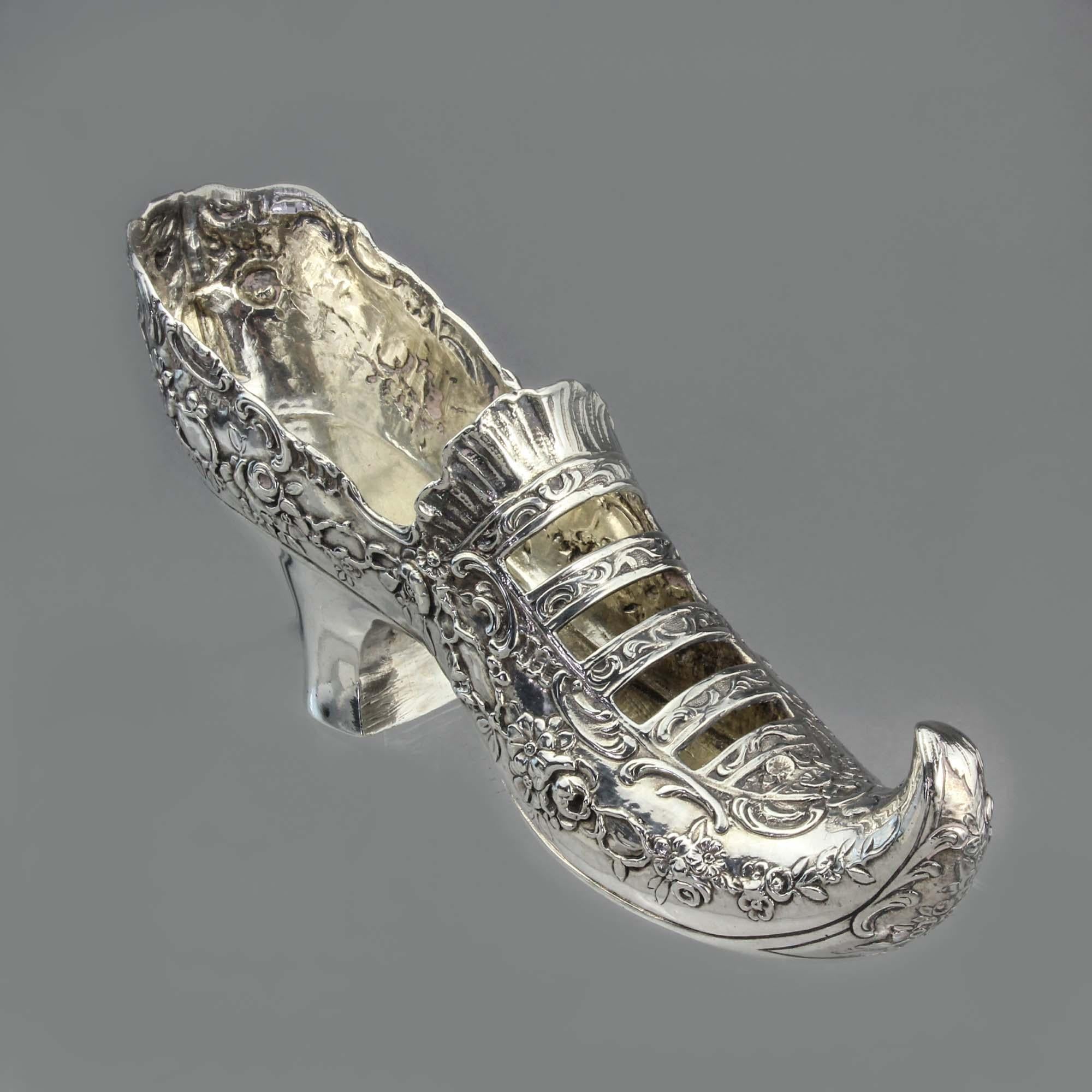Antique German 930. silver Rococo Lady's shoe with elf toe 

Shoe is with chased scrolls, floral garlands and open bands.

Made in Germany.
Maker: Gebruder Neumann 
Imported to England, London, 1896 by William Moering.

Dimensions:
15.5 x 4