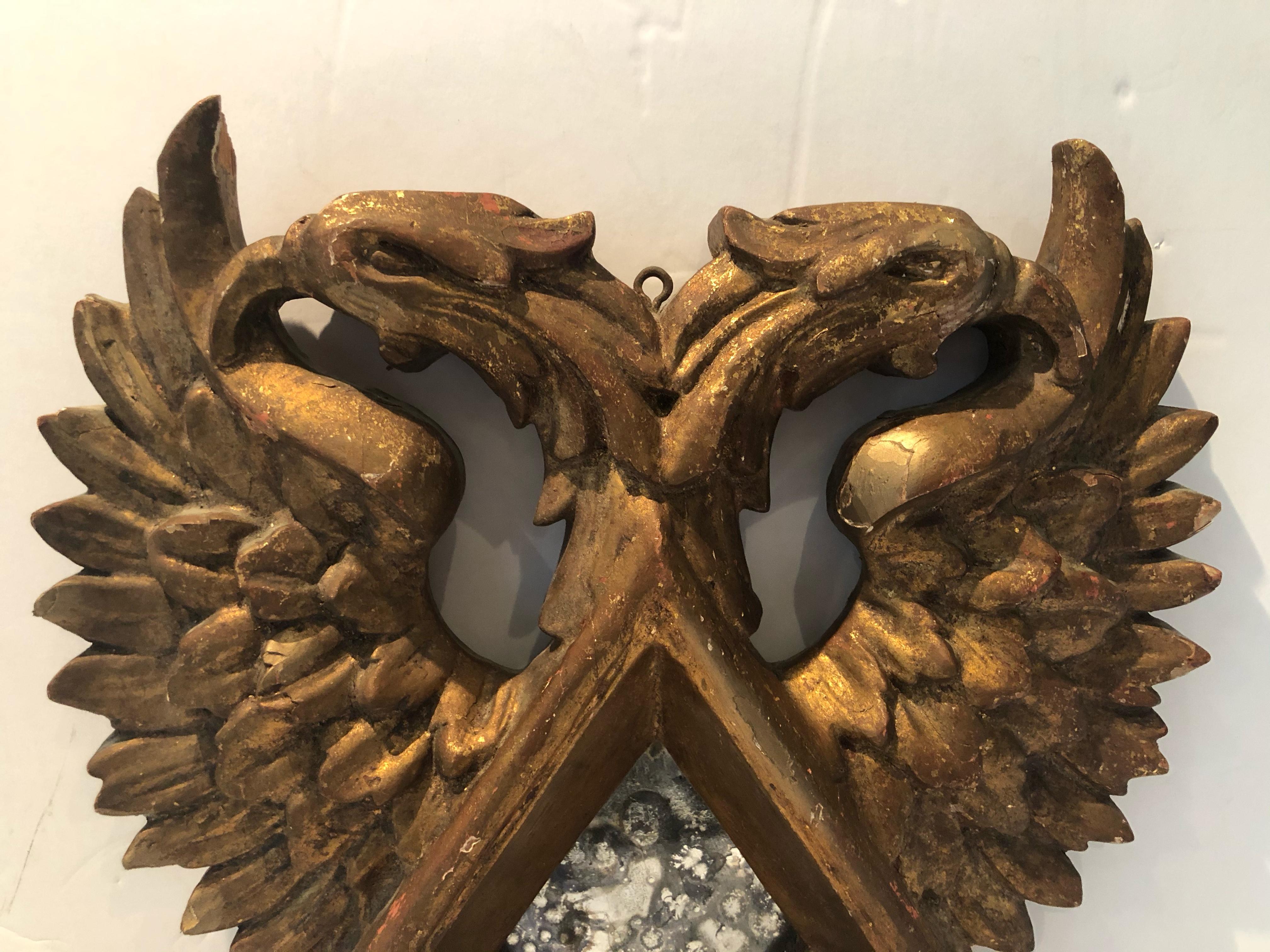 A very unique vintage giltwood mirror having an antiqued glass diamond shaped mirror in the center. The hand carving of this mirror is very detailed as can be seen in the wings and feet of the griffins. Griffins are mythological creatures having the