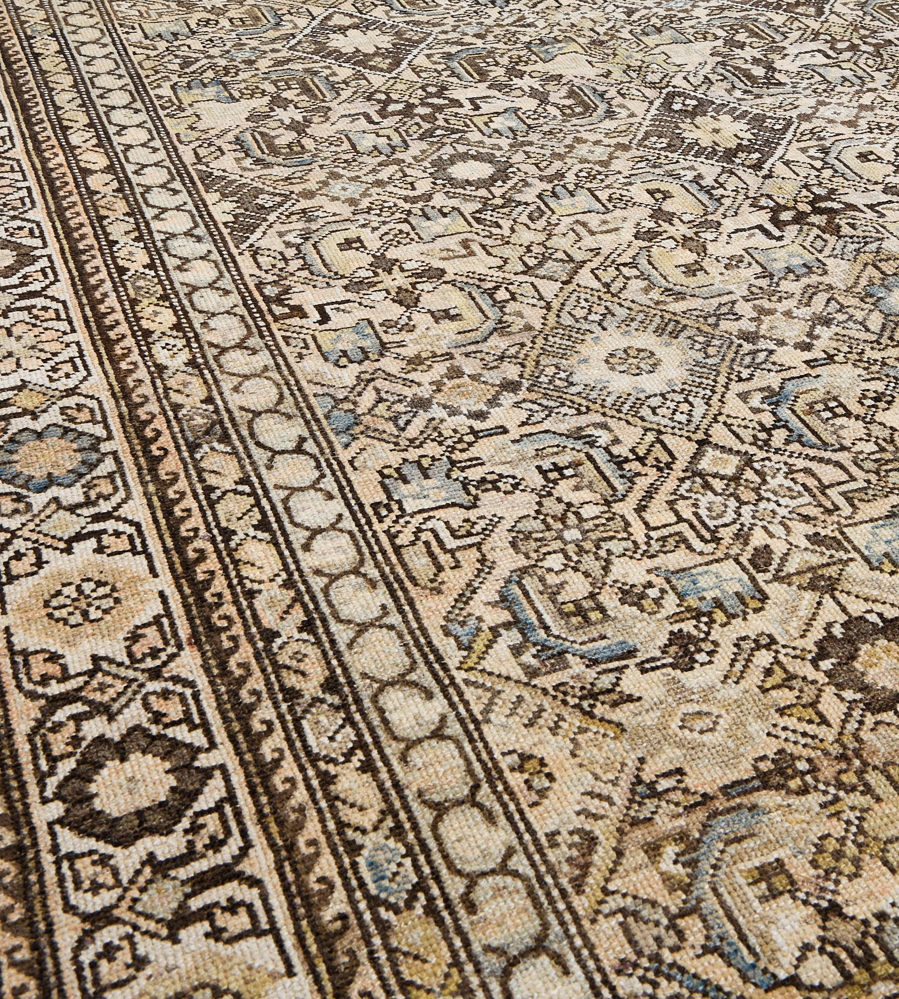 This antique Malayer rug has a sandy-yellow field with an overall fox-brown and light blue herati-pattern design, in an ivory border of angular pistachio-green, fox-brown and sandy-yellow palmette vine between chocolate-brown linked boteh and minor