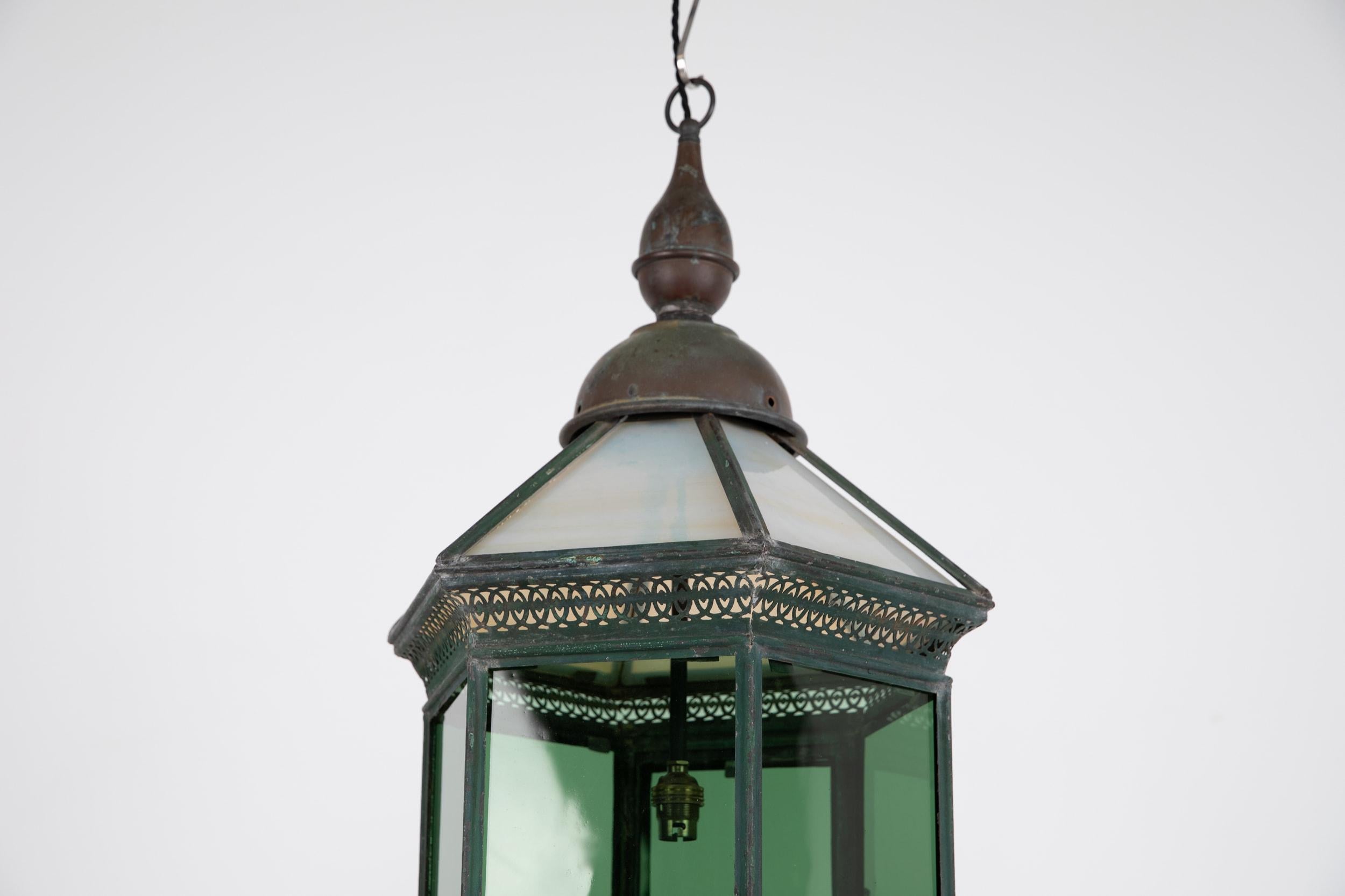 

Elegant metal lantern with original paint made in England. c.1890.

Dating to the late 19th Century with a beautiful patina to the original painted surface and unusual rolled green and opaline glass. Small flap to the underside where the