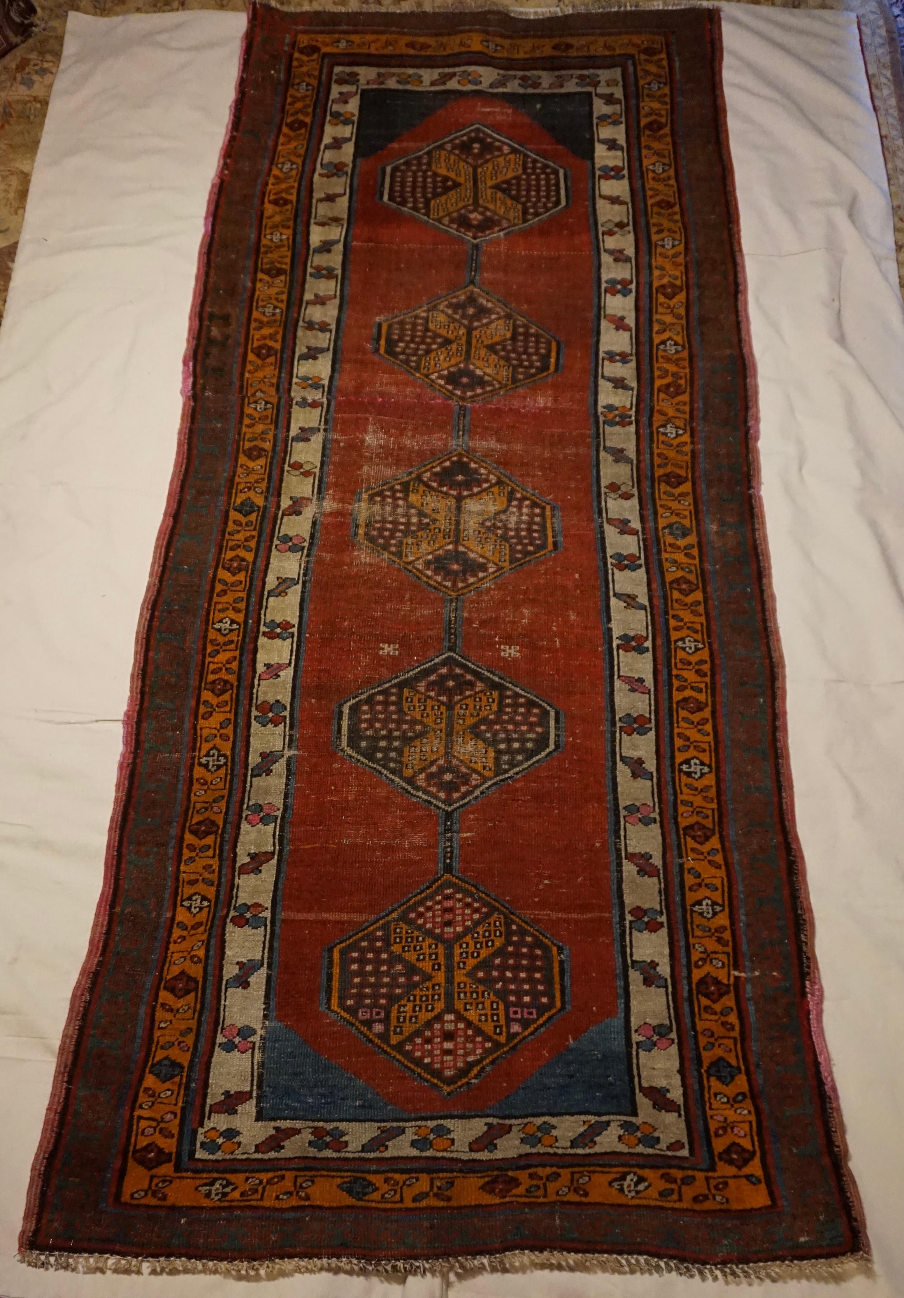 Beautiful late 19th Century Caucasus Tribal runner hand-knotted in natural dyed wool in pomegranate reds, ochre and turquoise. Bold pattern with a chain of kite shaped medallions encompassing honey comb designs. This rug has a few low pile spots and