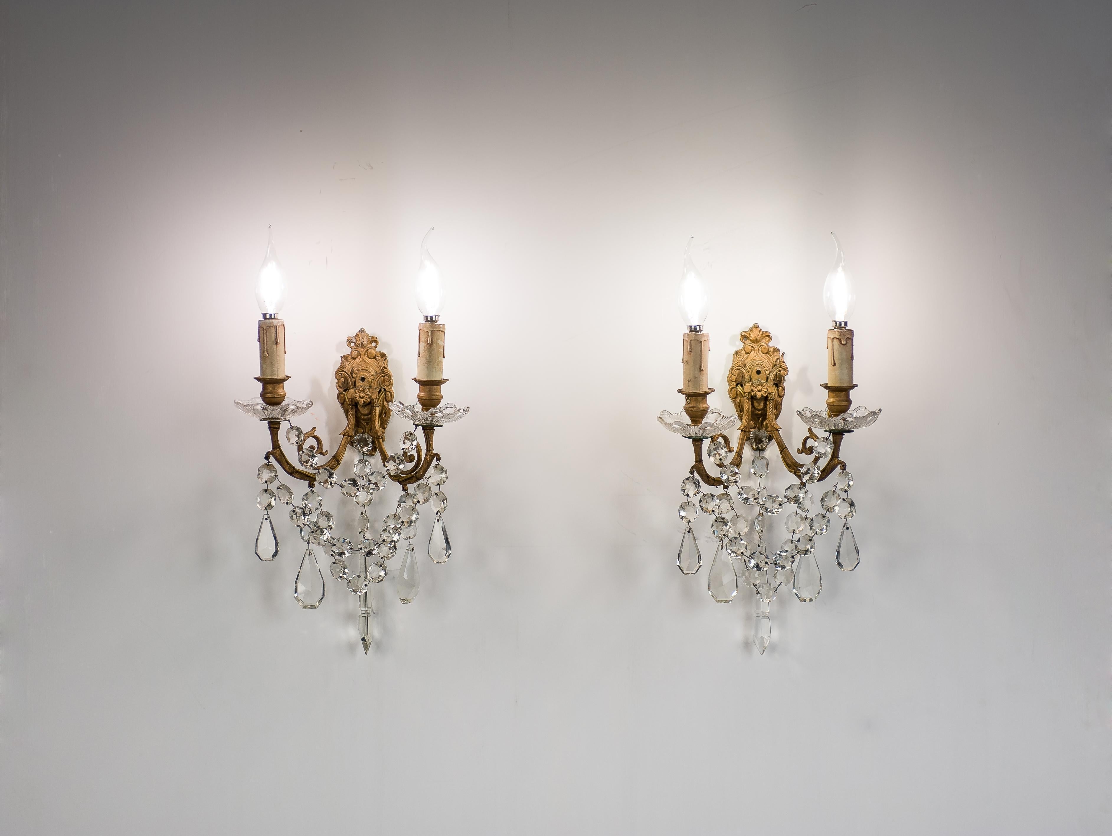 On offer here is a beautiful pair of antique late 19th-century wall sconces that were made in France circa 1880. The sconces feature a cast brass frame hung with baccarat crystal ornaments. This elegant baroque-style sconce features two scrolled