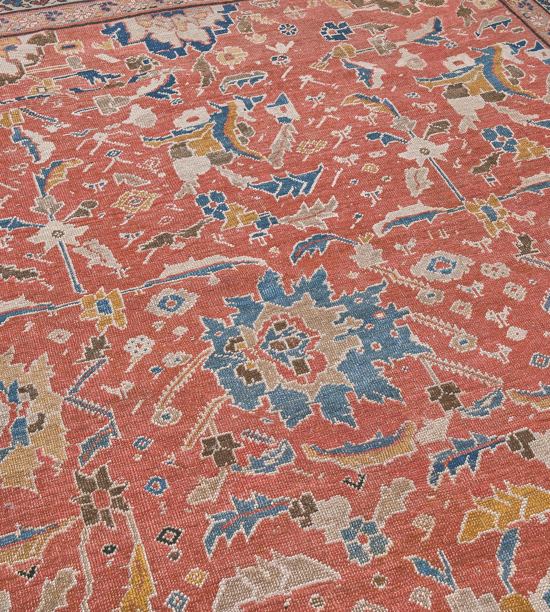 Questo tradizionale tappeto persiano Bakhshaish tessuto a mano presenta un campo rosso mattone sfumato con un disegno generale di palmette e viticci policromi, in un bordo blu medio di foglie e teste di fiori dentellati tra raffinate strisce di viti