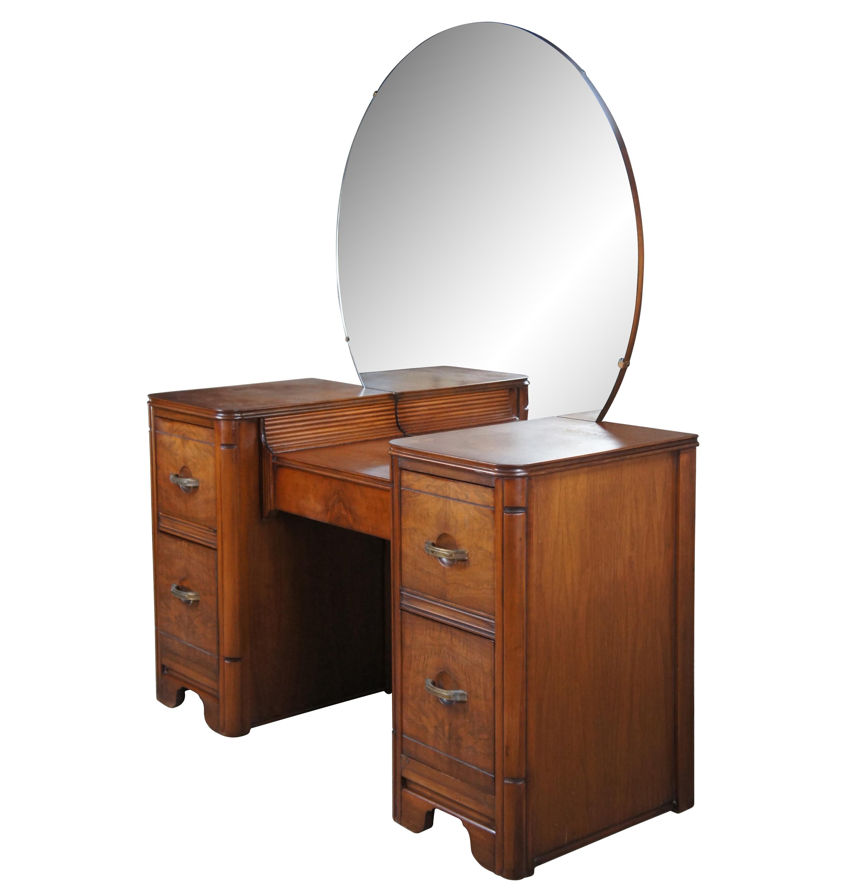 An impressive late Art Deco vanity or dressing table. Made from walnut with matchbook drawer fronts and round mirror with beveled edge. Includes four dovetailed drawers having unique concave impressions and shapely brass drawer pulls. Marked B 296-8