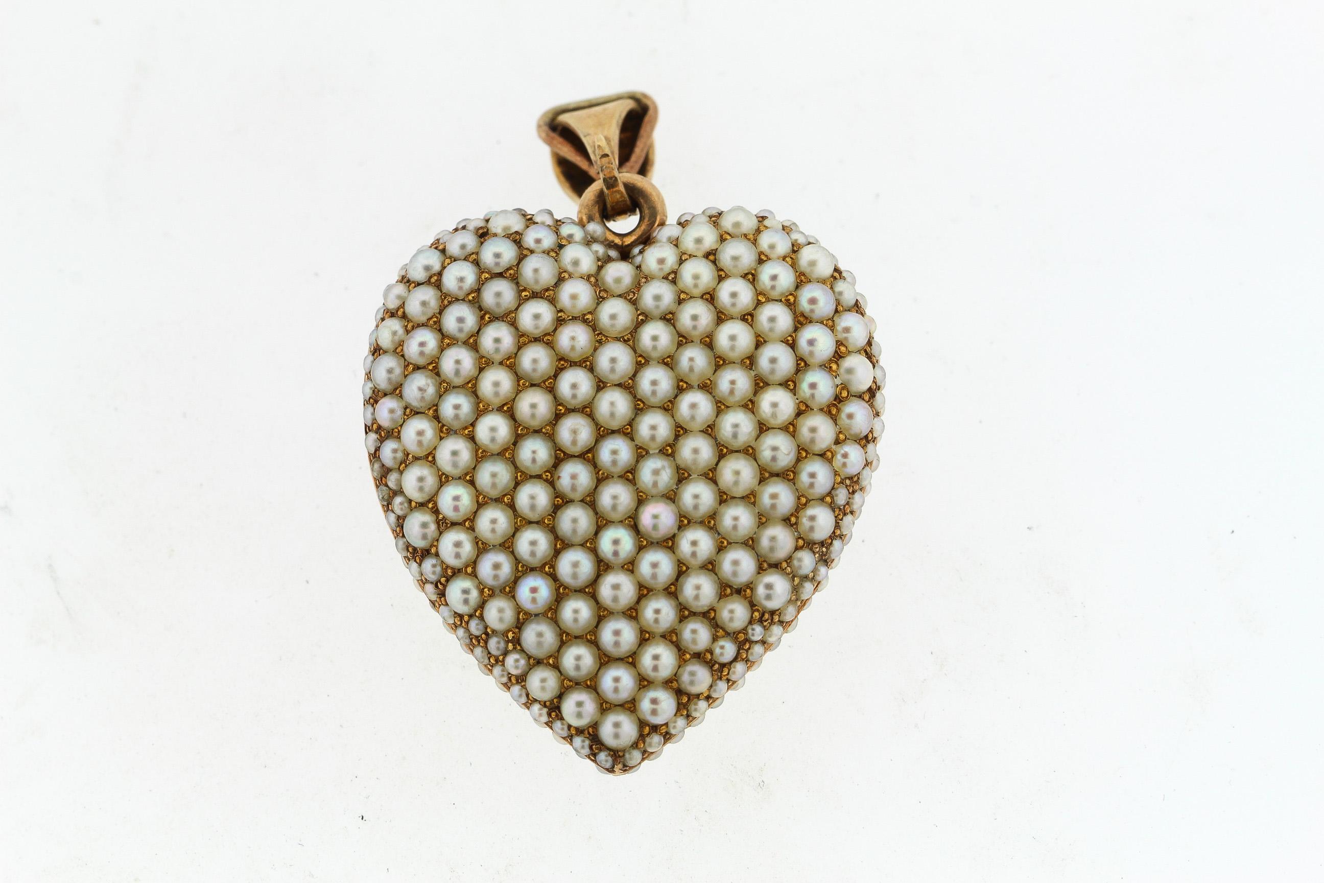 A beautiful antique 14k yellow gold white seed pearl heart locket, circa 1880. A wonderful example of such a locket, the seed pearls “pavee” the front and back of the locket. It opens and has the original crystal inside where a memento of hair or