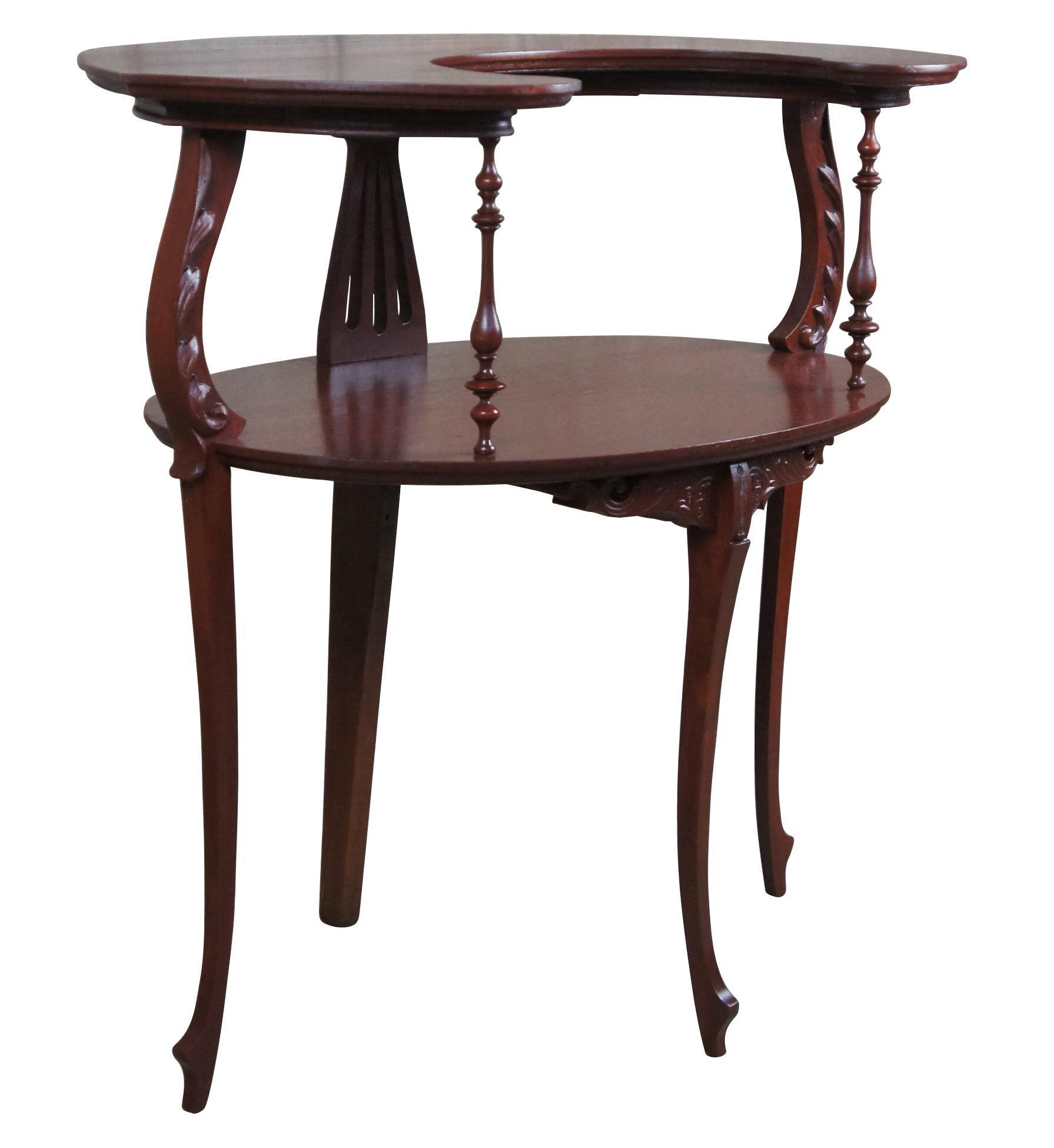 Elegant early 20th century oval tiered accent table. In the Victorian era these little tables were most often used for serving dessert. The table is made from mahogany with a crescent moon or demilune top surface supported by spindled, pierced and