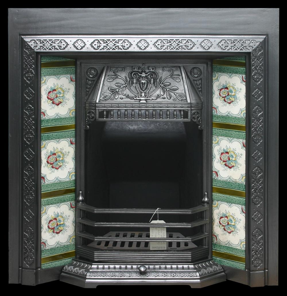 Antique late Victorian cast iron and tiled fireplace grate with a ladies mask to the canopy above fine spindles.

Finished with traditional black grate polish and ready for a solid fuel fire, complete with new clay fire back and cast iron bottom