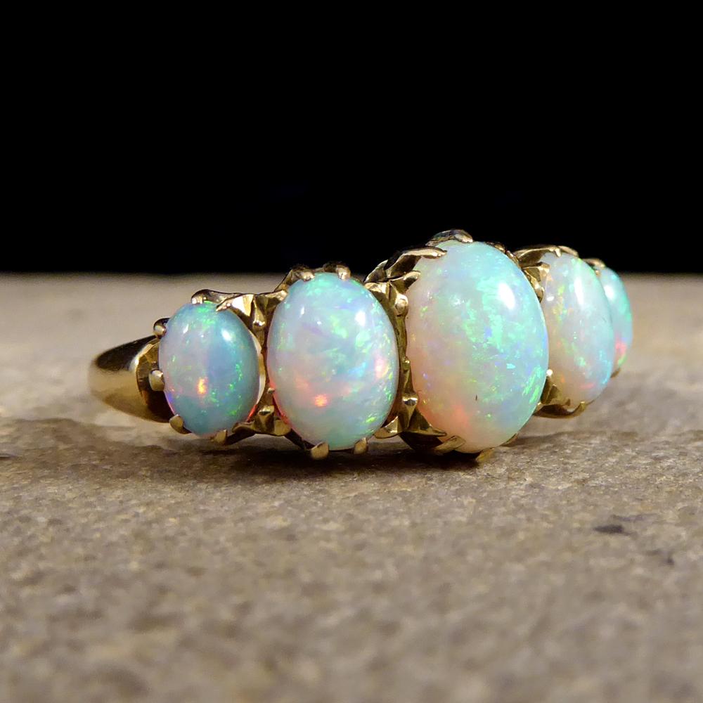 This lovely Late Victorian Ring has Five Opal stones which are graduating in size with the centre stone being the largest. Showing greens oranges and blues and held securely into place in a claw setting, this ring has been crafted from 18ct Yellow