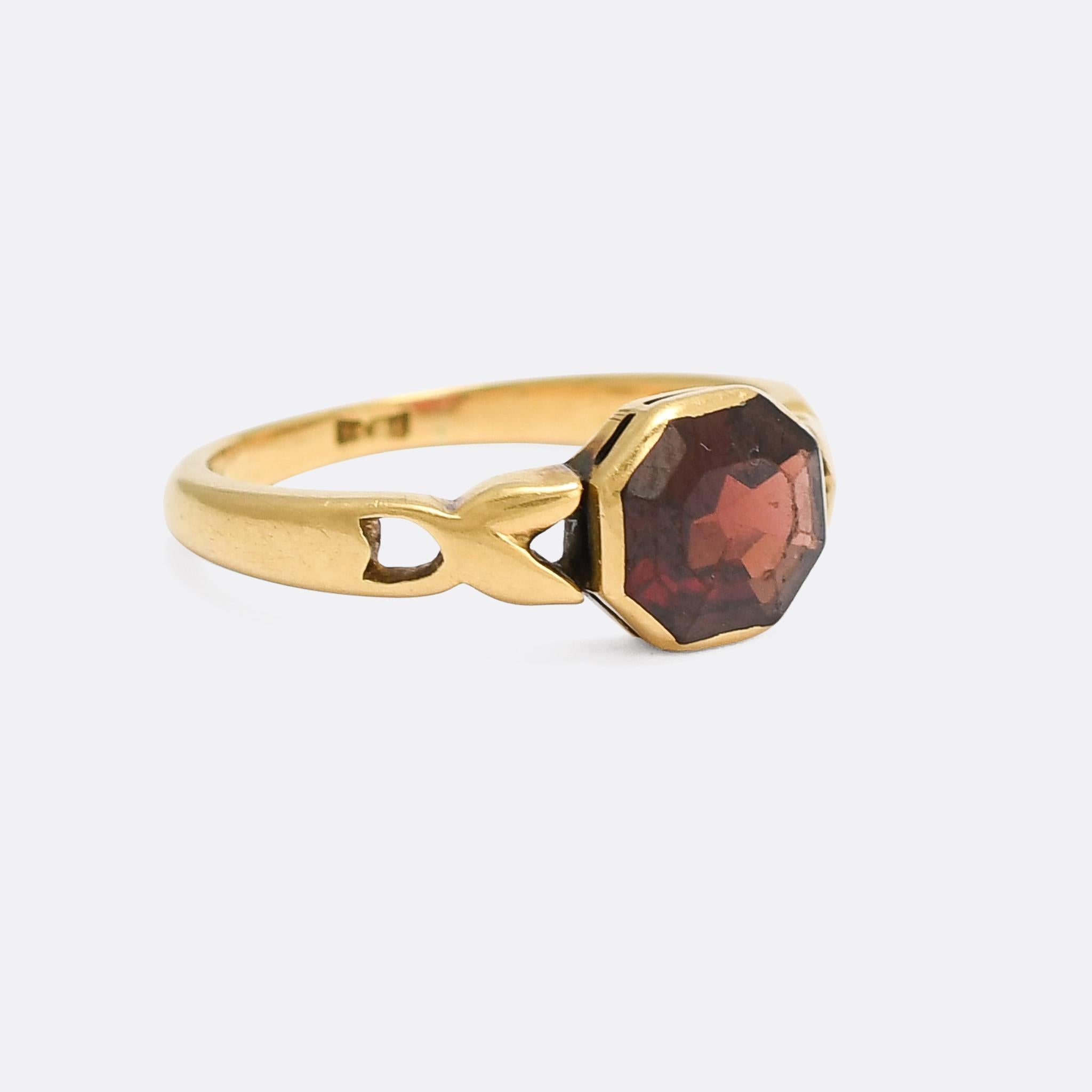 An unusual and alluring antique garnet ring dating from the late Victorian period, circa 1890. The stone is an octagonal faceted pyrope garnet, a particularly bright blood-red example, collet set in an 18 karat gold ring mount. The band features