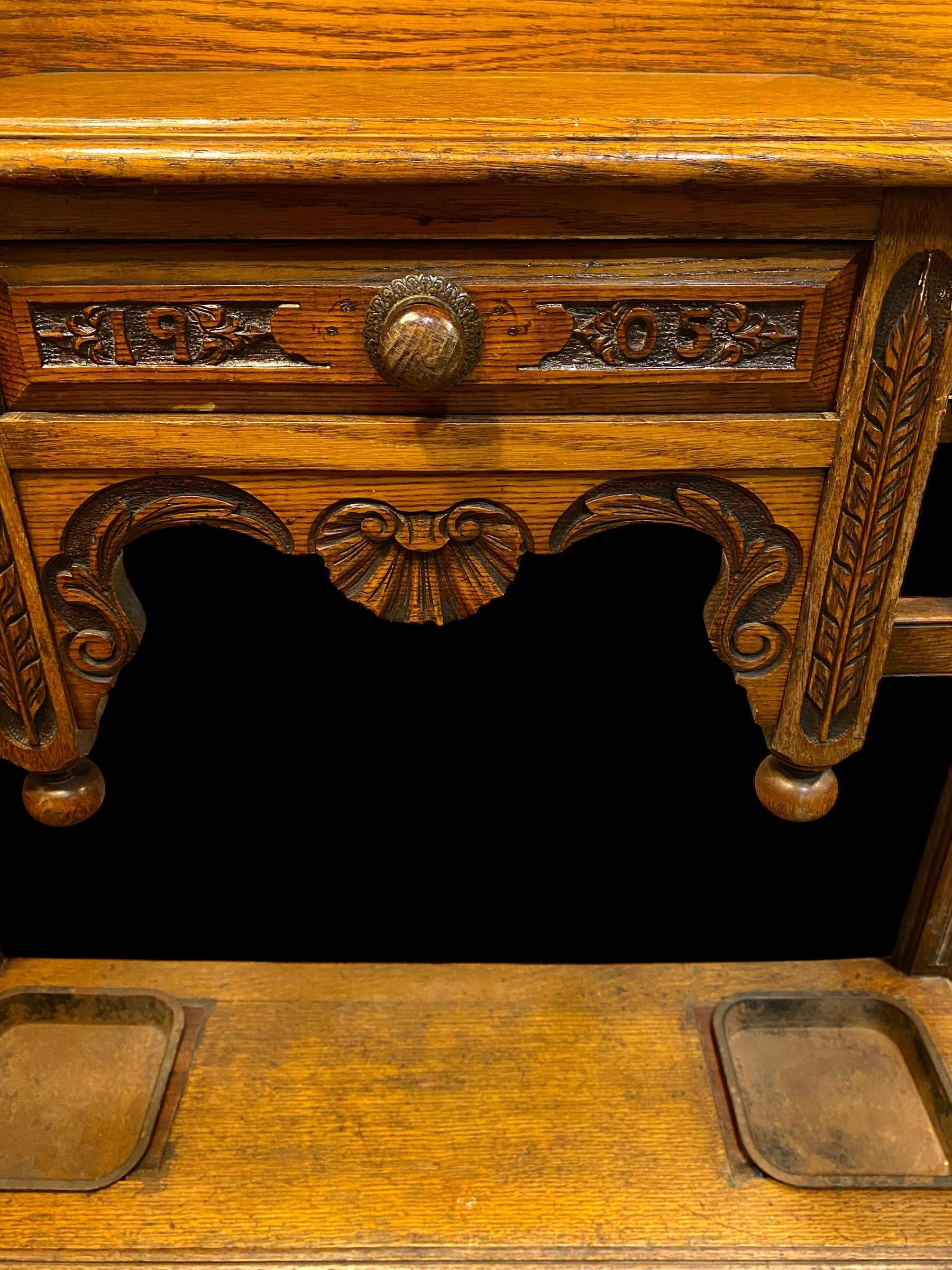 A handsome example of a late Victorian hall stand created from solid oak, mirror and iron. This is a very useful antique that has everything you will need in your hall, an original double-bevelled glass mirror to check your appearance before you go