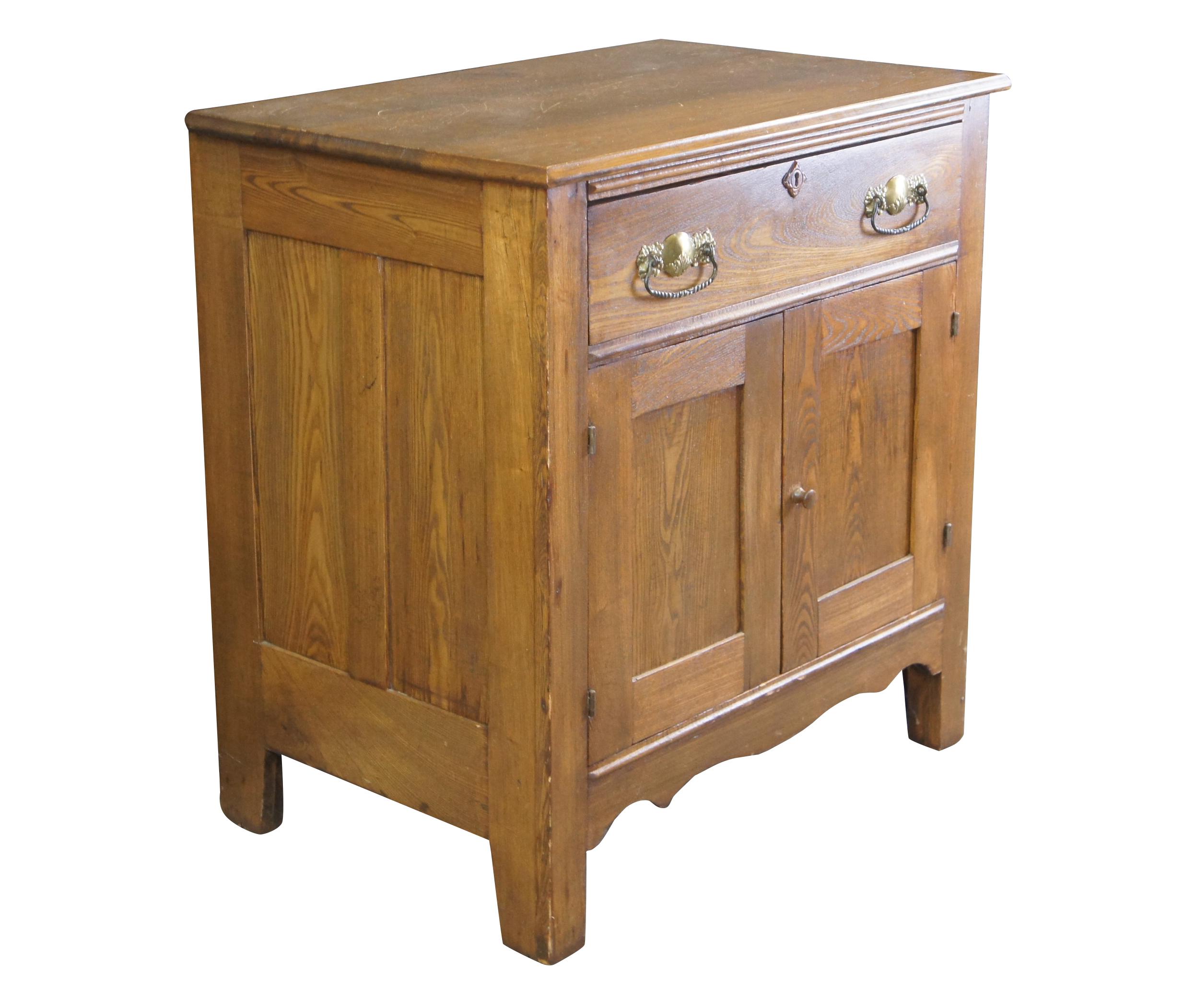 A quaint Victorian Era Washstand.  Made from oak with one dovetailed drawer featuring ornate brass hardware and lower cabinet for storage.  The drawer has a neat diamond carved key escutcheon