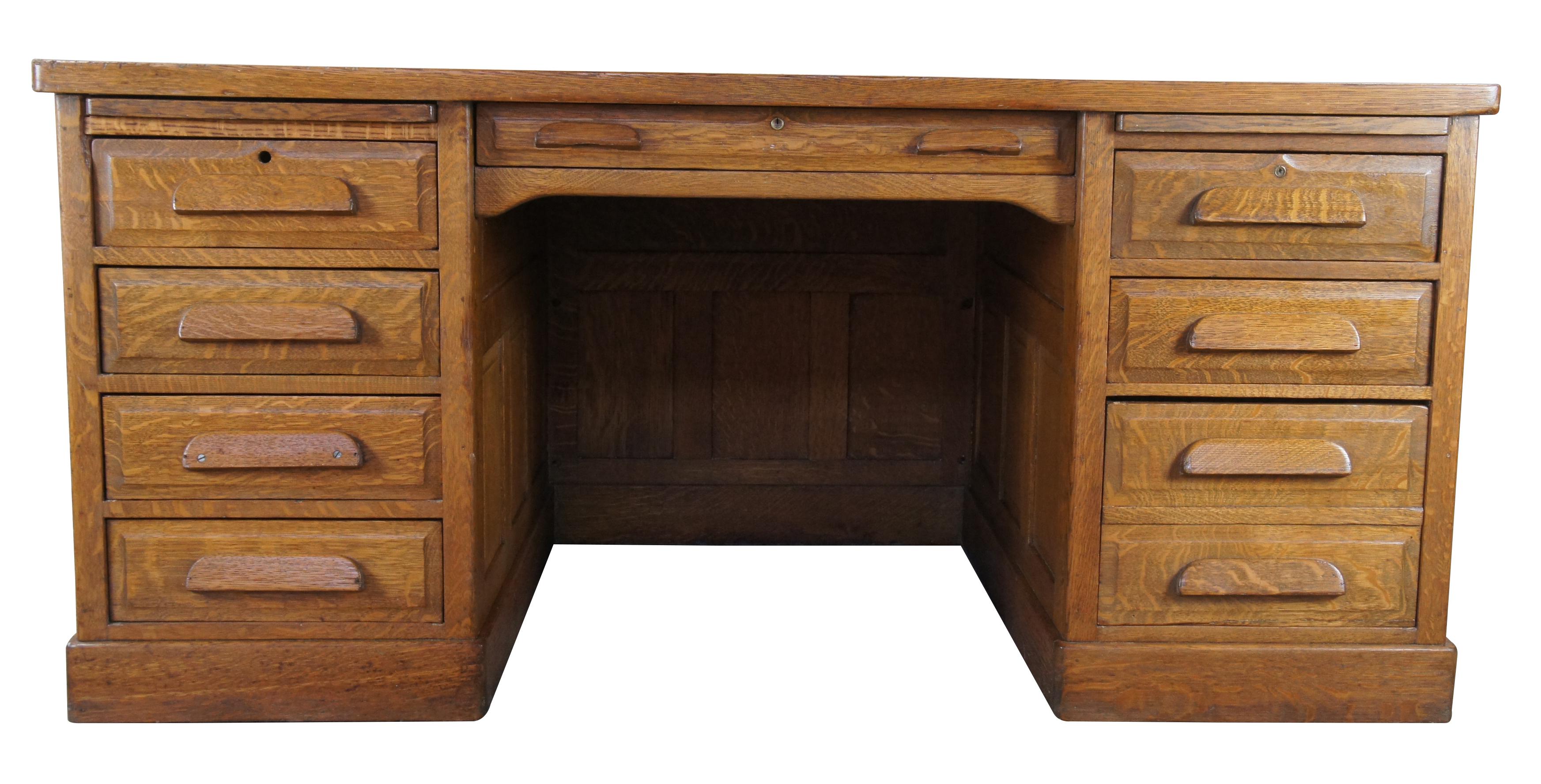 Antique late Victorian oak executive desk. Made of quartersawn oak featuring rectangular form with paneled exterior, large central drawer flanked by six drawers, one file cabinet drawer and two pull out writing surfaces.

Measures: 65