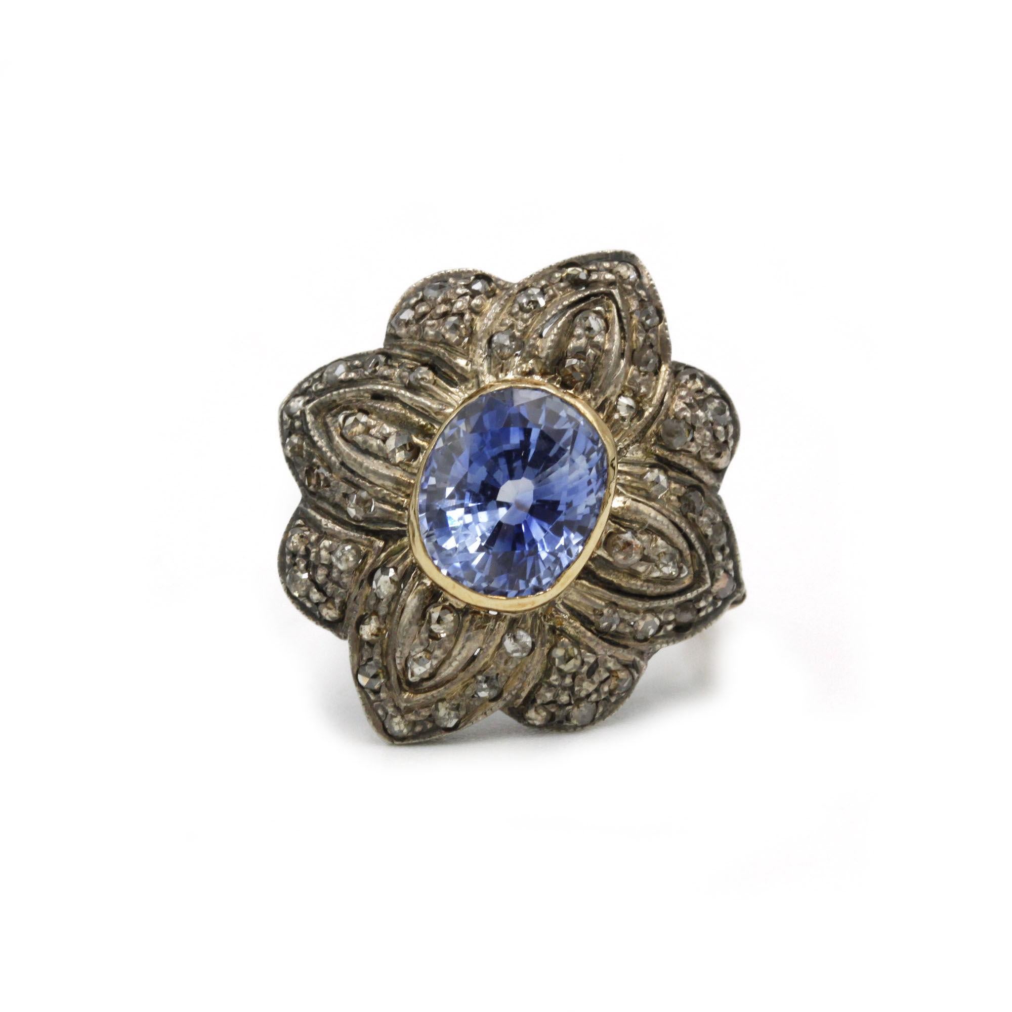 This exceptional Late Victorian cluster ring showcases a richly hued, unheated Ceylon sapphire of approximately 3.50 carats, bezel-set in warm 9K yellow gold. Surrounding the central gem is an intricately pierced sterling-silver floral motif, each