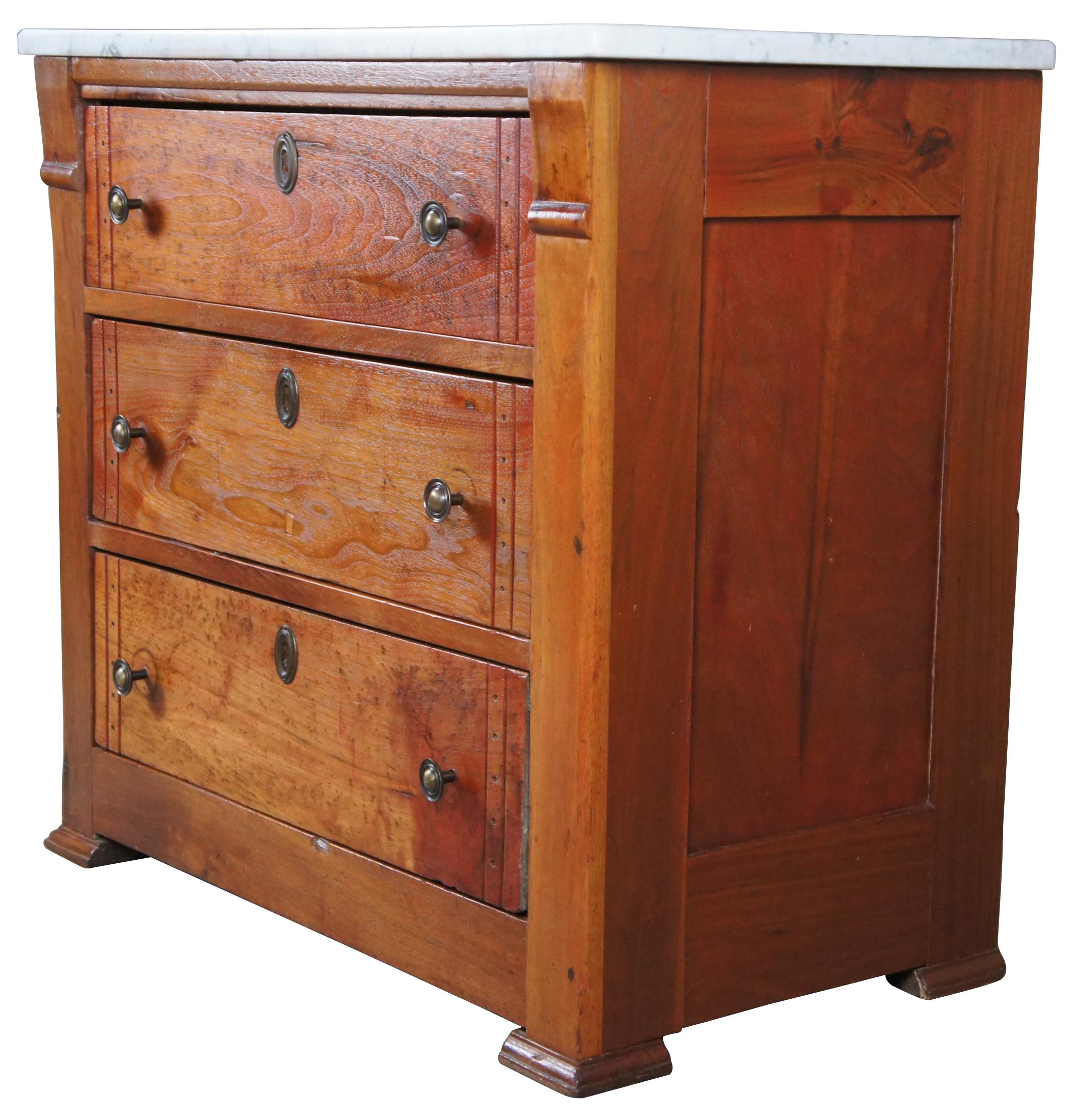 Early 20th century washstand or dresser. Made from walnut with 3 dovetailed drawers and a white marble top. Drawer fronts have a unique vertical punched design.