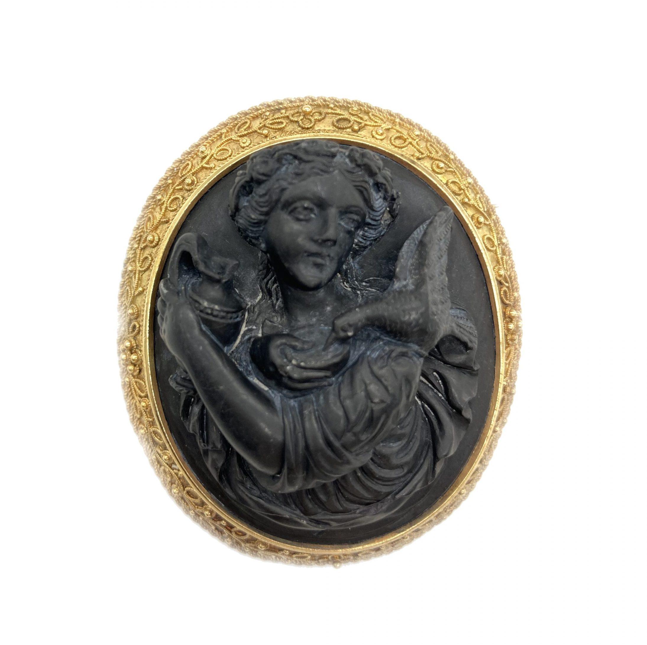 A nineteenth century yellow gold brooch featuring a carved lava cameo encircled by granulated gold in the archaeological revival style.