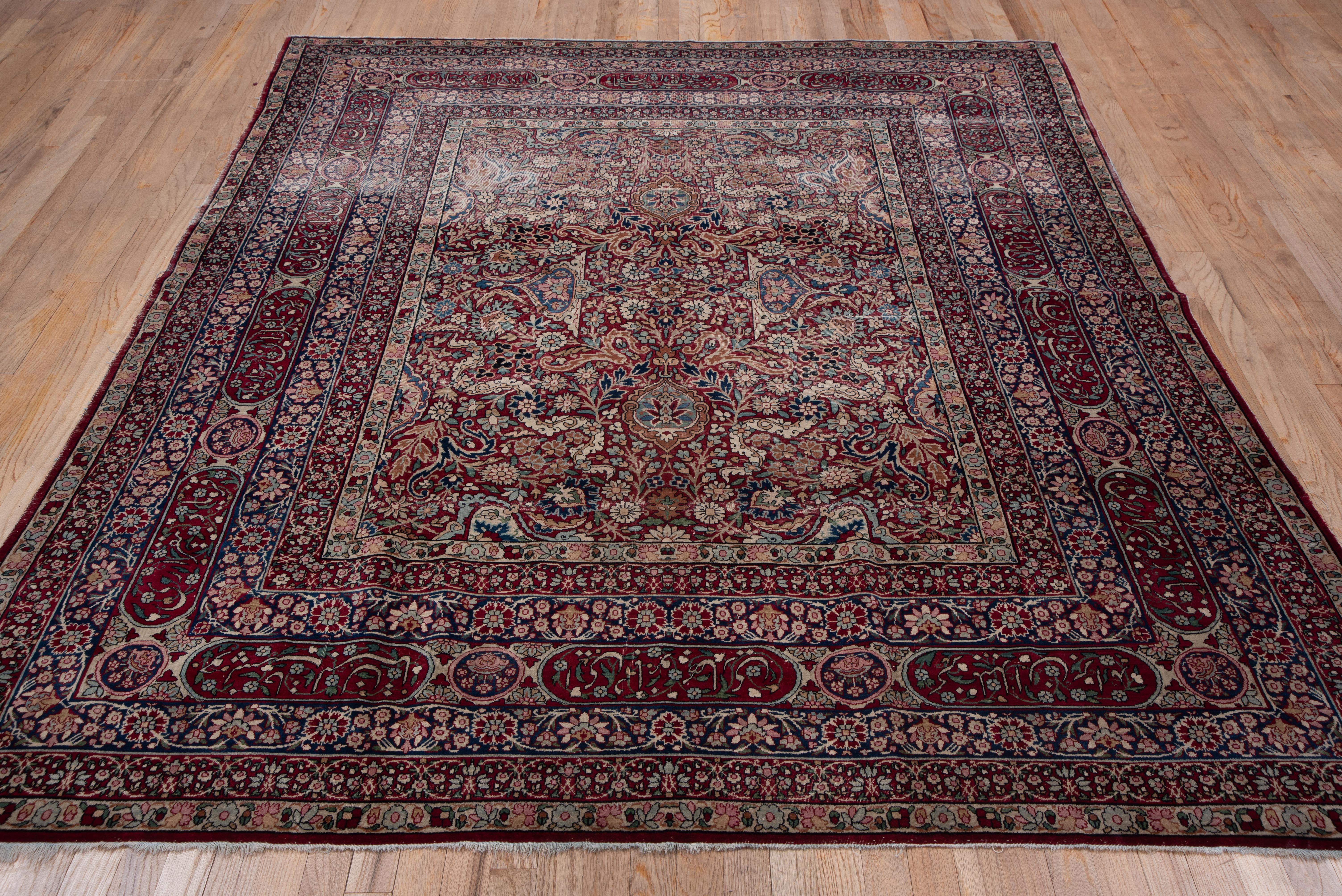 Finely woven, this Lavar quality large scatter from the famous SE Persian rug weaving center of Kerman, shows the characteristic cochineal scarlet field very closely covered by split arabesques, scalloped ovals, escutcheons and a wide variety of