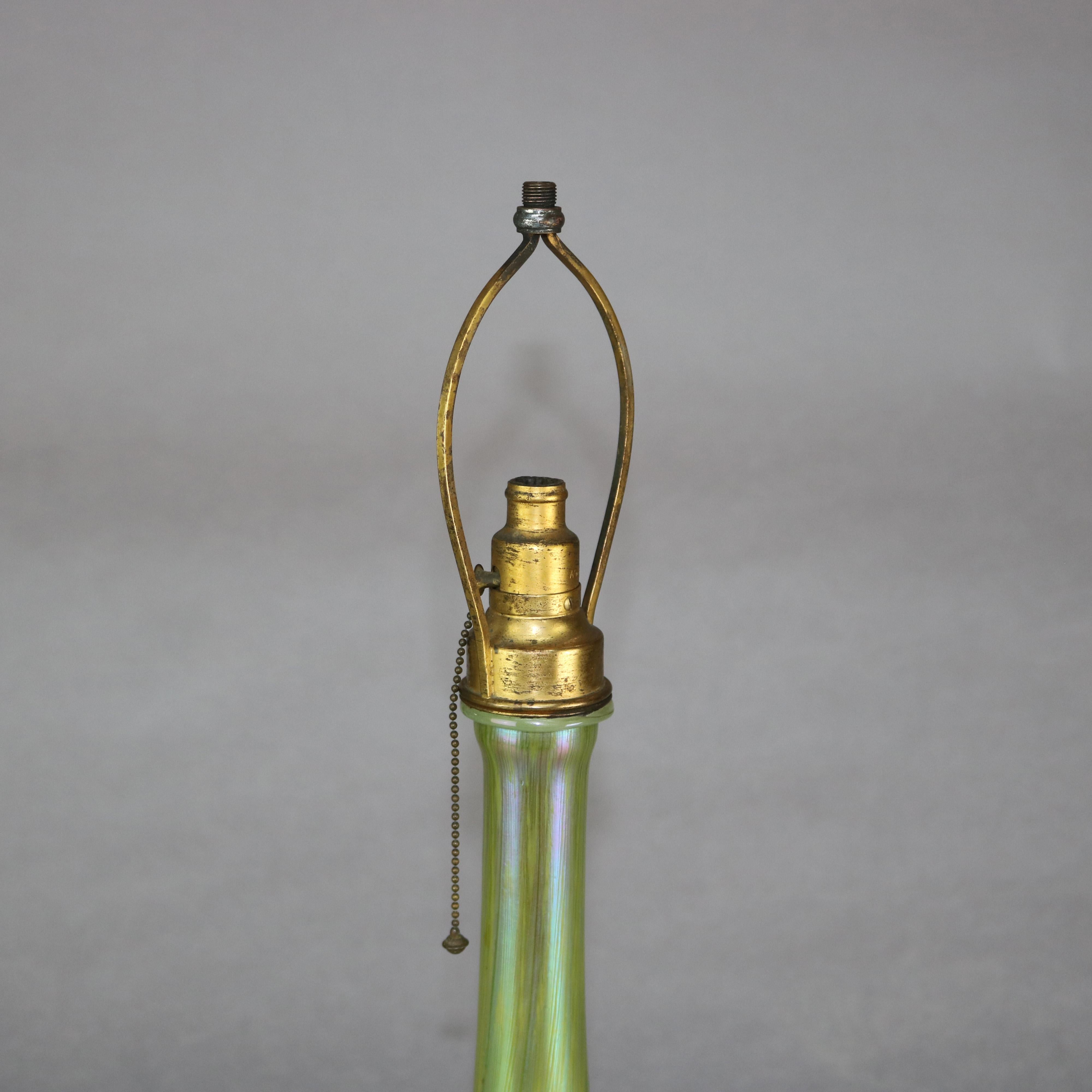 An antique Favrile art glass single socket table lamp base by L.C. Tiffany offers flared form with green, white and gold pulled feather design, signed on base as photographed, circa 1920

Measures: 17.5