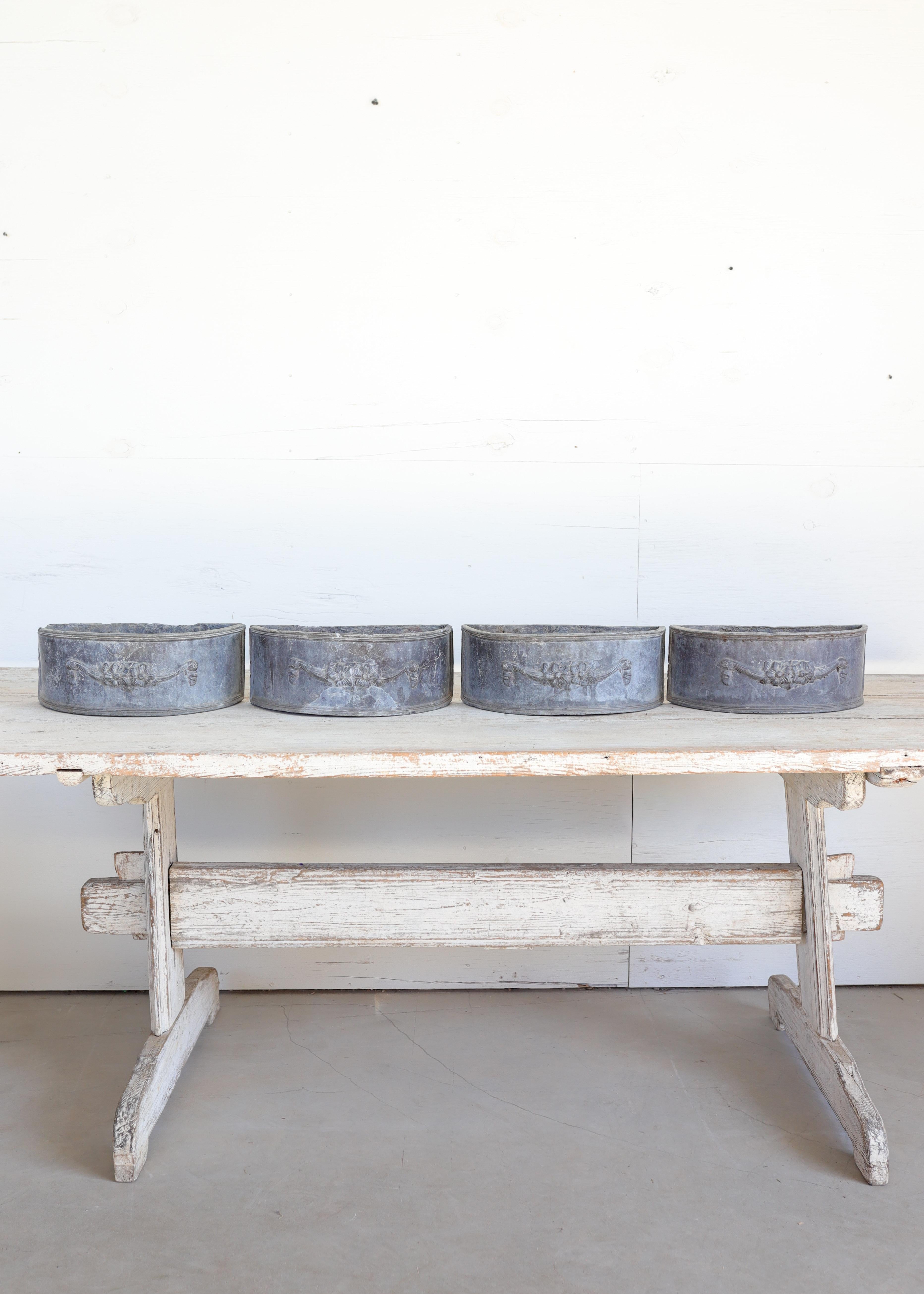 A rare and elegant set of four antique lead planters, each beautifully adorned with classical floral swag motifs in high relief. Crafted in heavy cast lead, these planters exemplify timeless European garden design—substantial in weight, gracefully