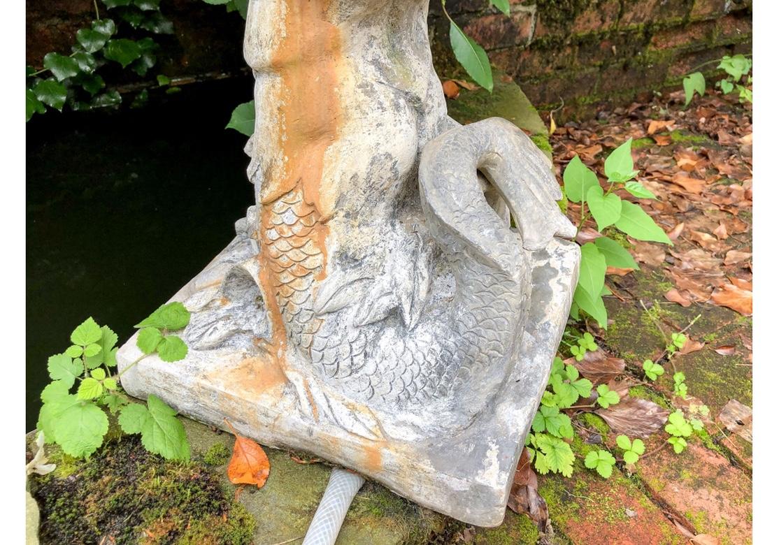 Antique garden figure of Triton with his scrolled dolphin tail blows into a shell shaped horn that forms the fountain. On a square base.
Measures: height 28