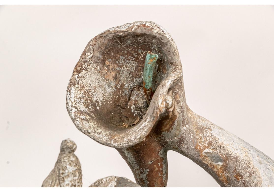 The kneeling figure of Triton with his fish tail legs blows a curved shell as a Horn. He wears a band with sea shells across his chest and his legs are covered with sea grasses. In his left hand he holds a sea creature by its neck. He was part of