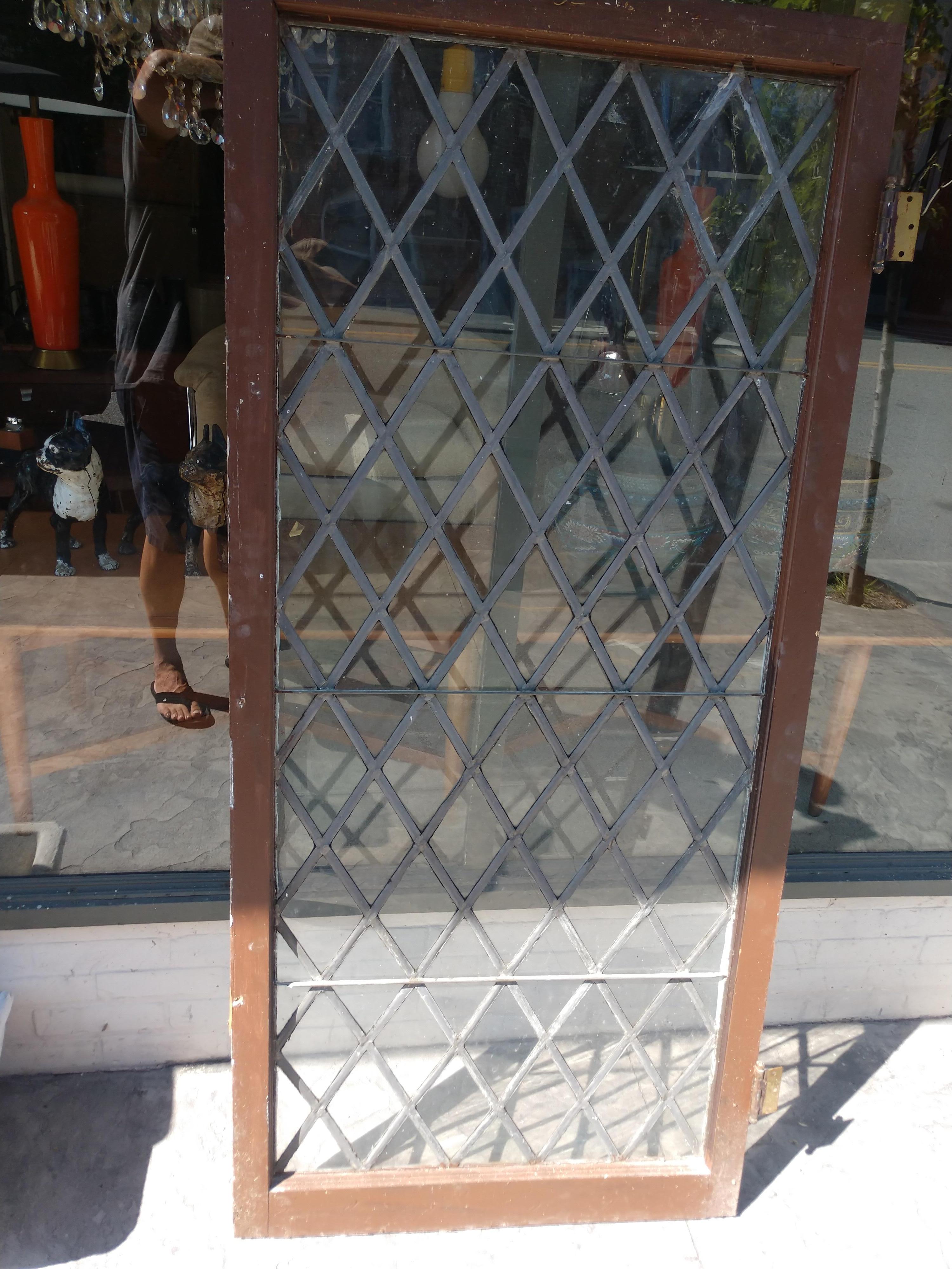 Diamond shaped window with leaded frame. Hinged on sides. Excellent vintage condition with minimal wear. Glazing around the outer frame is old and cracked, needs refreshing.