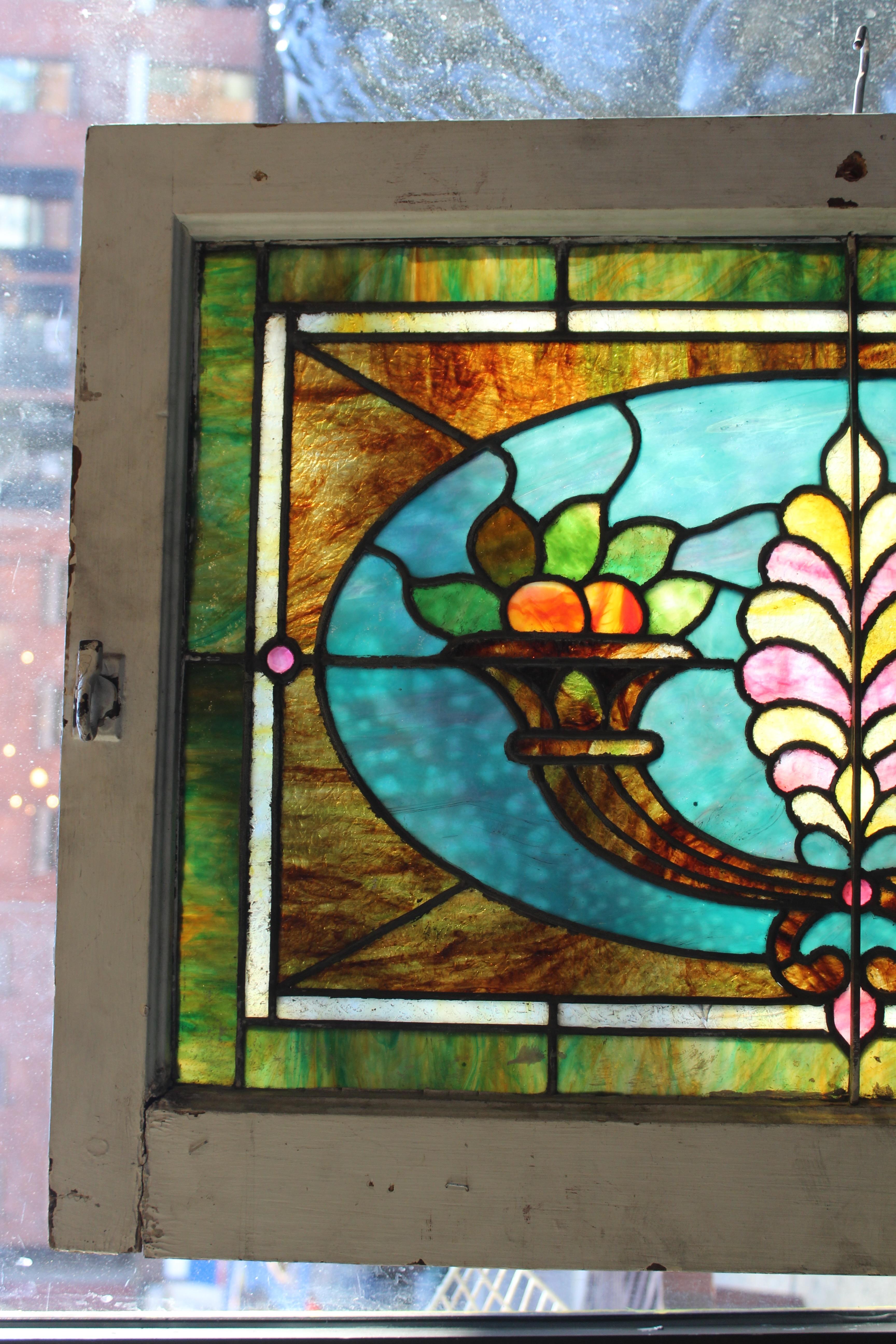 This window features richly stained glass panels that make a colorful design of fluted cornucopias. Marbled and textured glass give ample privacy while allowing light to poor into your home.
Currently housed in a wooden frame - the overall