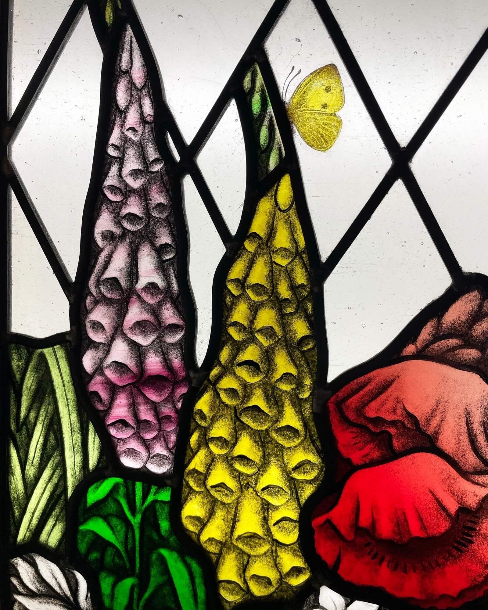 A beautiful early 20th century antique leaded glass window in the Arts and Crafts style depicting an array of colourful English flowers and flora including poppies, foxgloves, bluebells, daisies, tulips and butterflies. This window is in excellent
