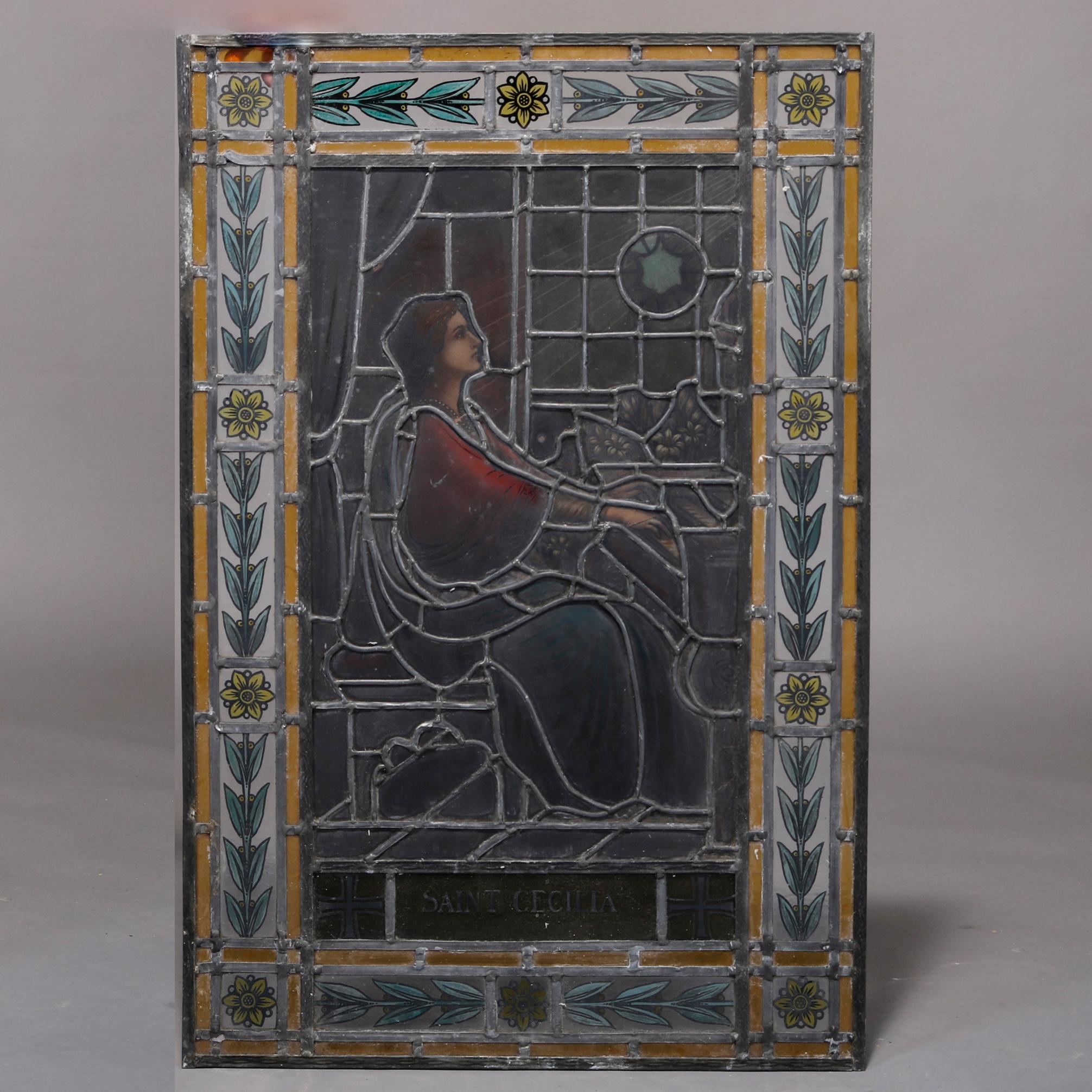 An antique leaded and hand painted stained glass window depicts Saint Cecilia seated at her piano, title panel and foliate decorated frame as photographed, architectural element, 19th century

Measures: 39