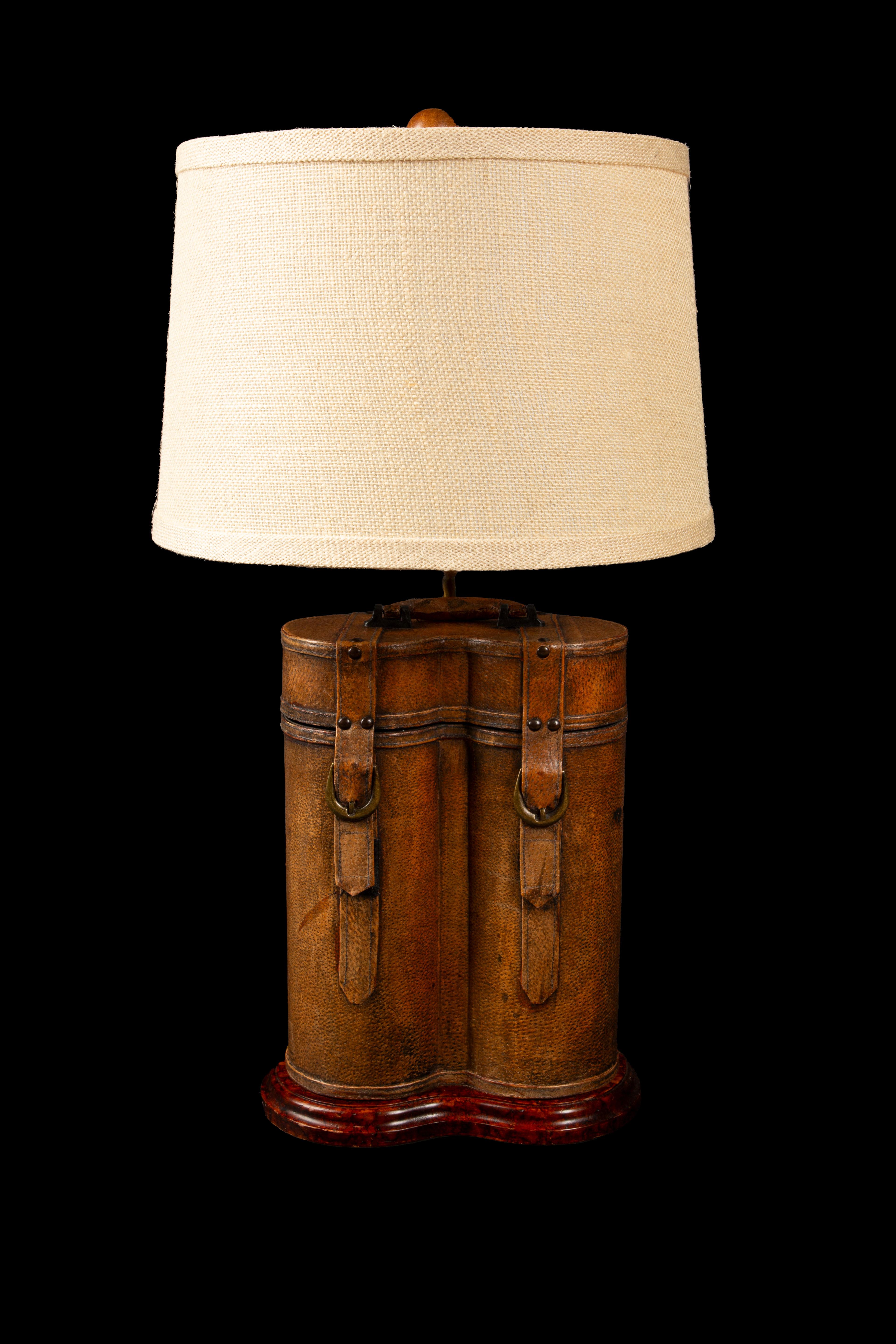 This exquisite 19th-century antique leather double bottle wine holder has been ingeniously repurposed and transformed into a stunning lamp, seamlessly blending history and functionality. Crafted with meticulous attention to detail, the rich patina