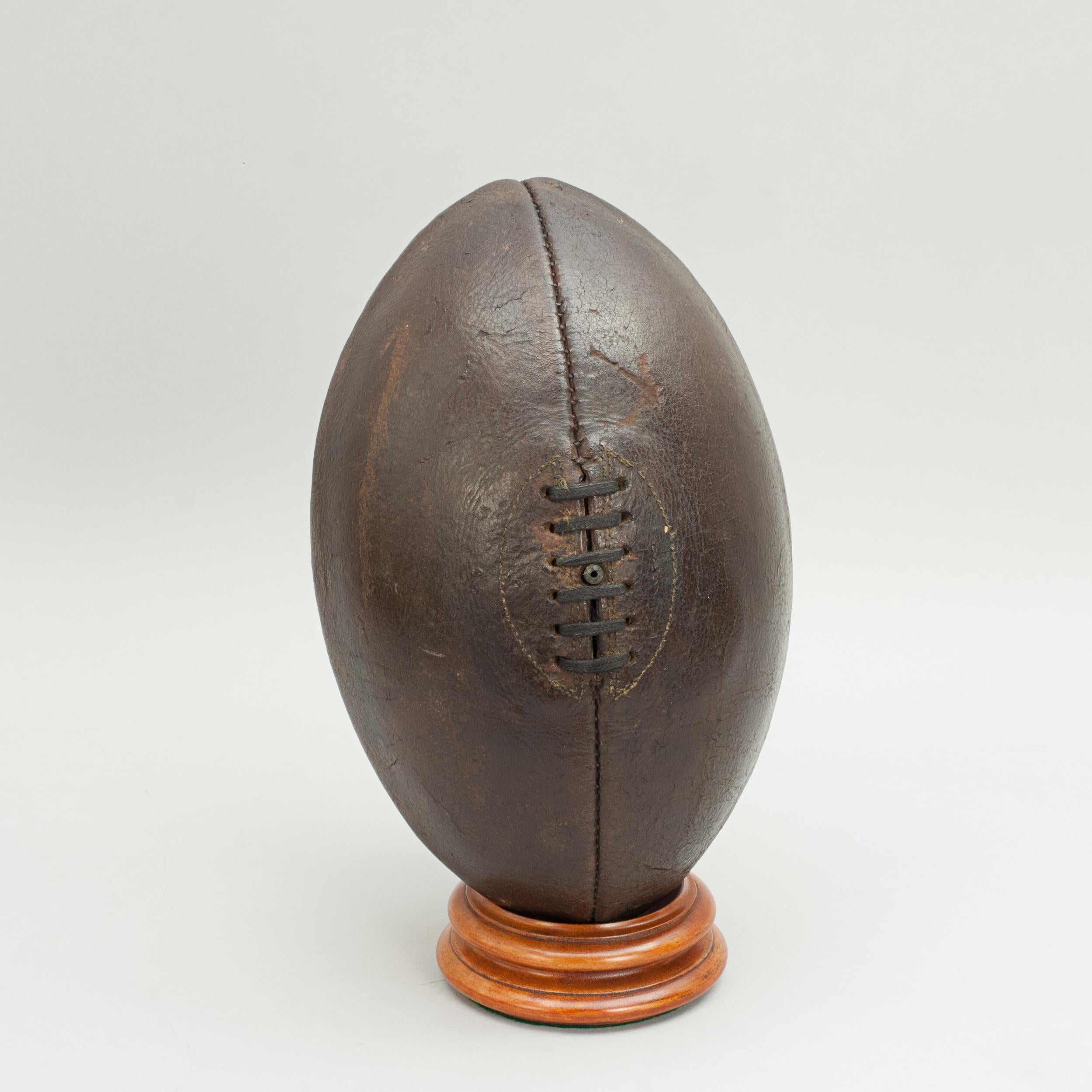 Early leather rugby ball.
A traditional four panel leather rugby ball with a lace-up slit to the top and valve for bladder inflation. The ball is with good dark color and patination.

Stand sold separately.