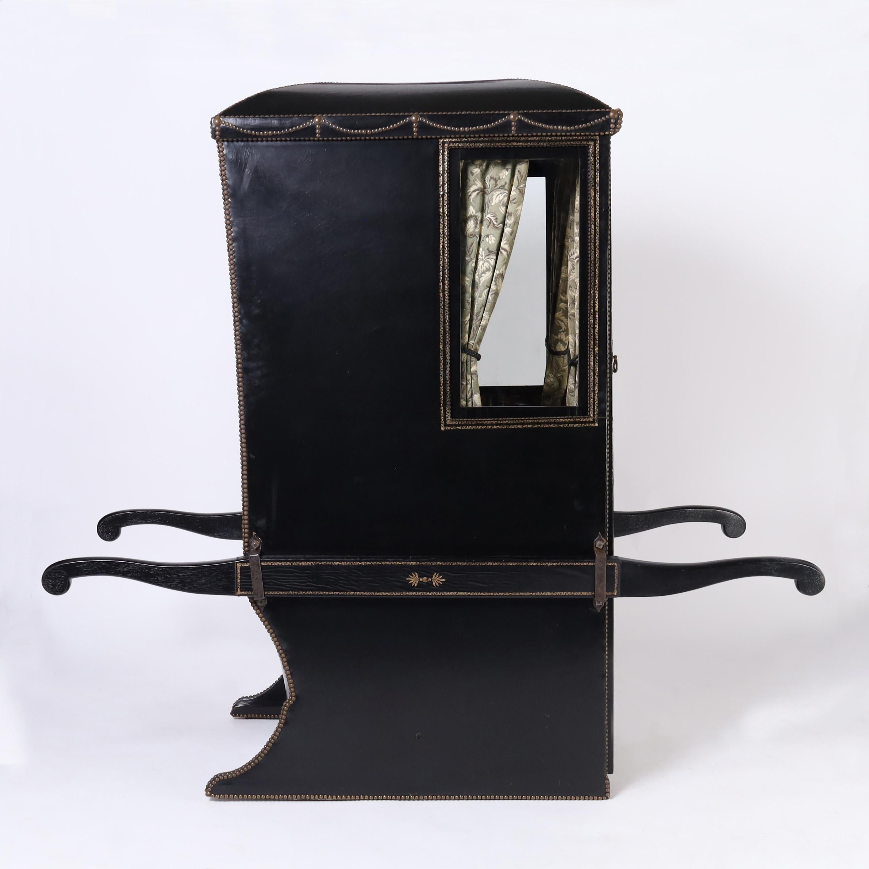 Arrive in style in this rare and remarkable 19th century luxurious English sedan chair entirely clad in tooled black leather decorated with brass tacks and featuring a brown leather interior with a button tufted seat over a secret compartment and