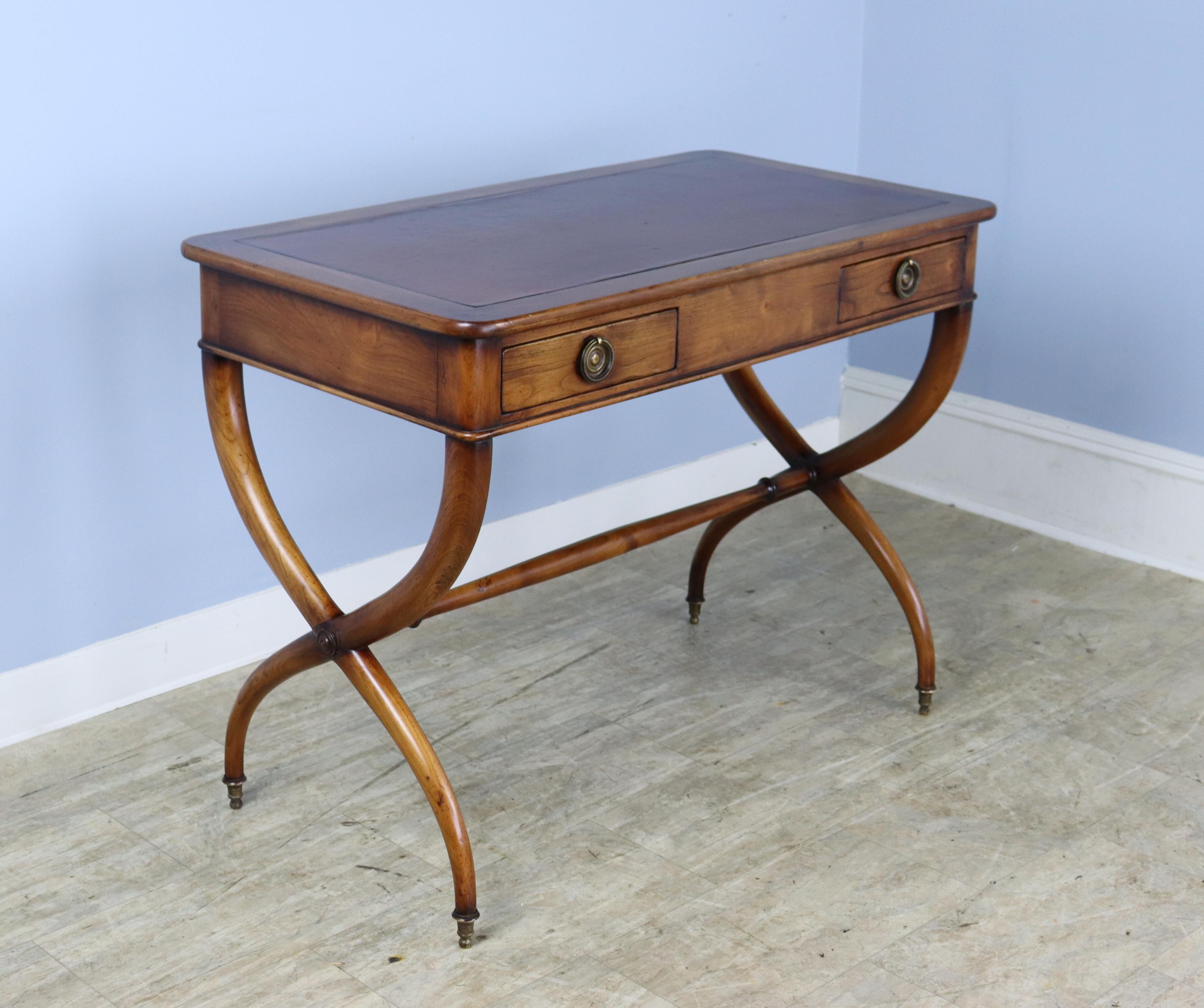 A fabulous mahogany writing table with original leather top and crossed sabre legs. The color and patina of the legs is very good. Original brass feet.