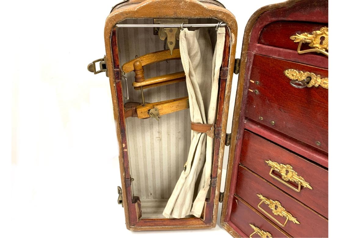 Une rare et ancienne malle de voyage en cuir et bois nervuré, échantillon de vendeur de garde-robe, avec un intérieur magnifiquement aménagé. La malle est dotée de coins arrondis coiffés de laiton, de poignées latérales en cuir, de loquets avec clé,