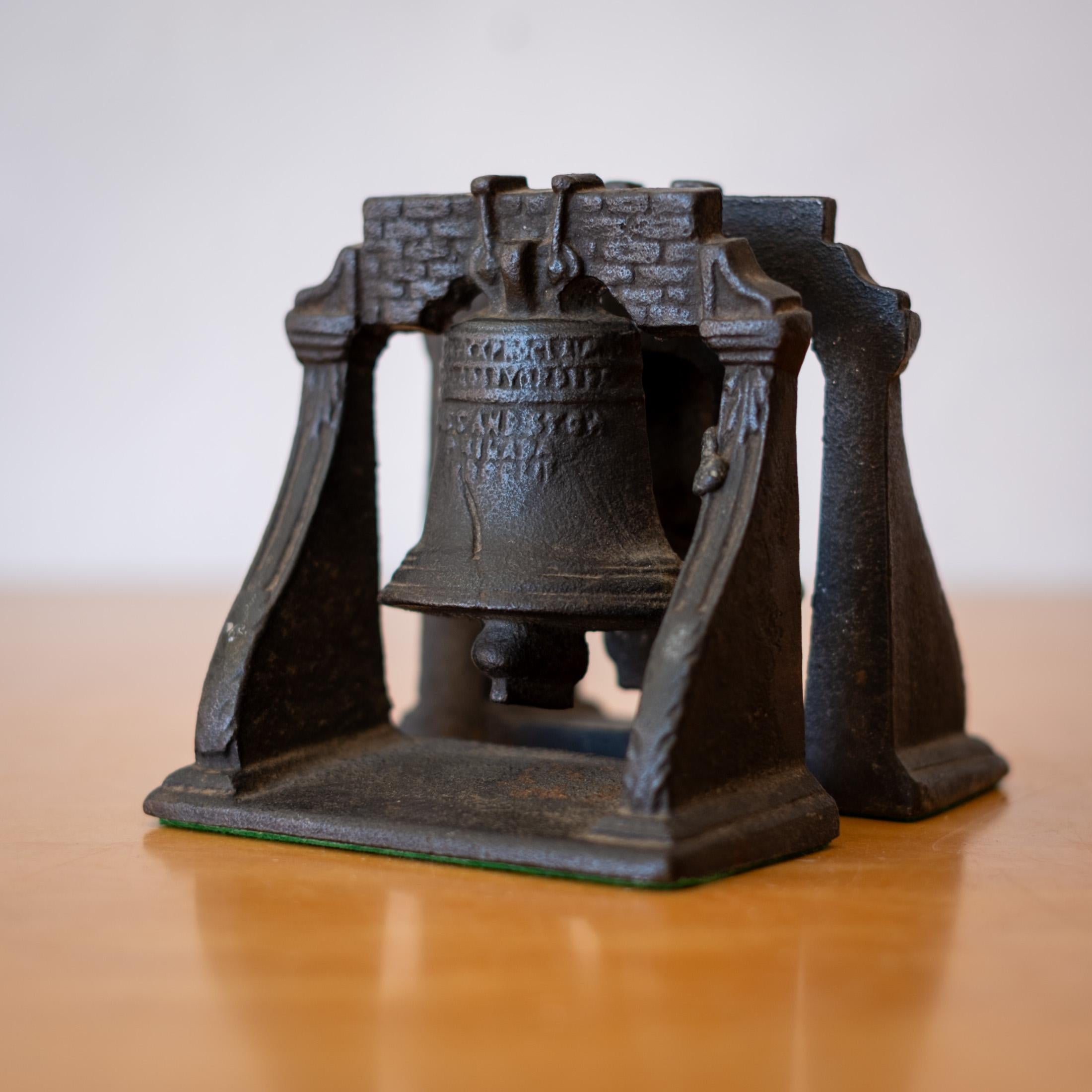 Una coppia di fermalibri liberty antichi in ferro massiccio con una bella patina.  Fondo in feltro verde. Senza segno. 

La Liberty Bell reca il messaggio: Proclamate la libertà in tutta la terra a tutti i suoi abitanti.

La campana della State