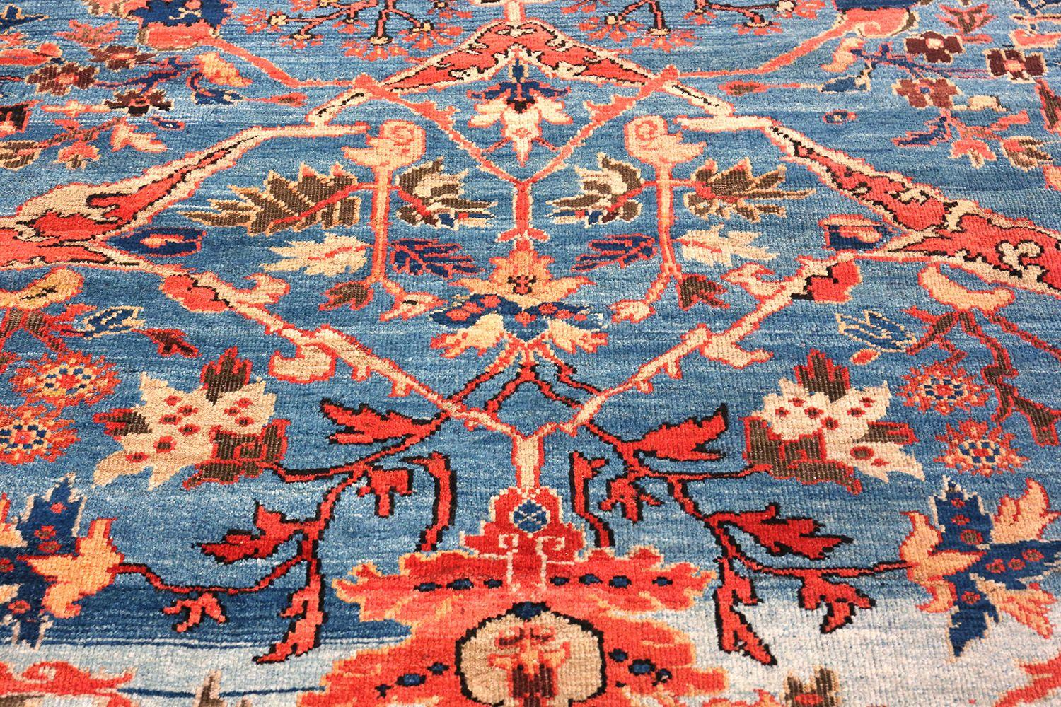 This magnificent antique Sultanabad rug from Persia possesses a beautiful design of classic Persian arabesque vine scrolls that sprawl beautifully across a lovely field of blue, the patina of which alternates between rich and dark hues, ephemeral