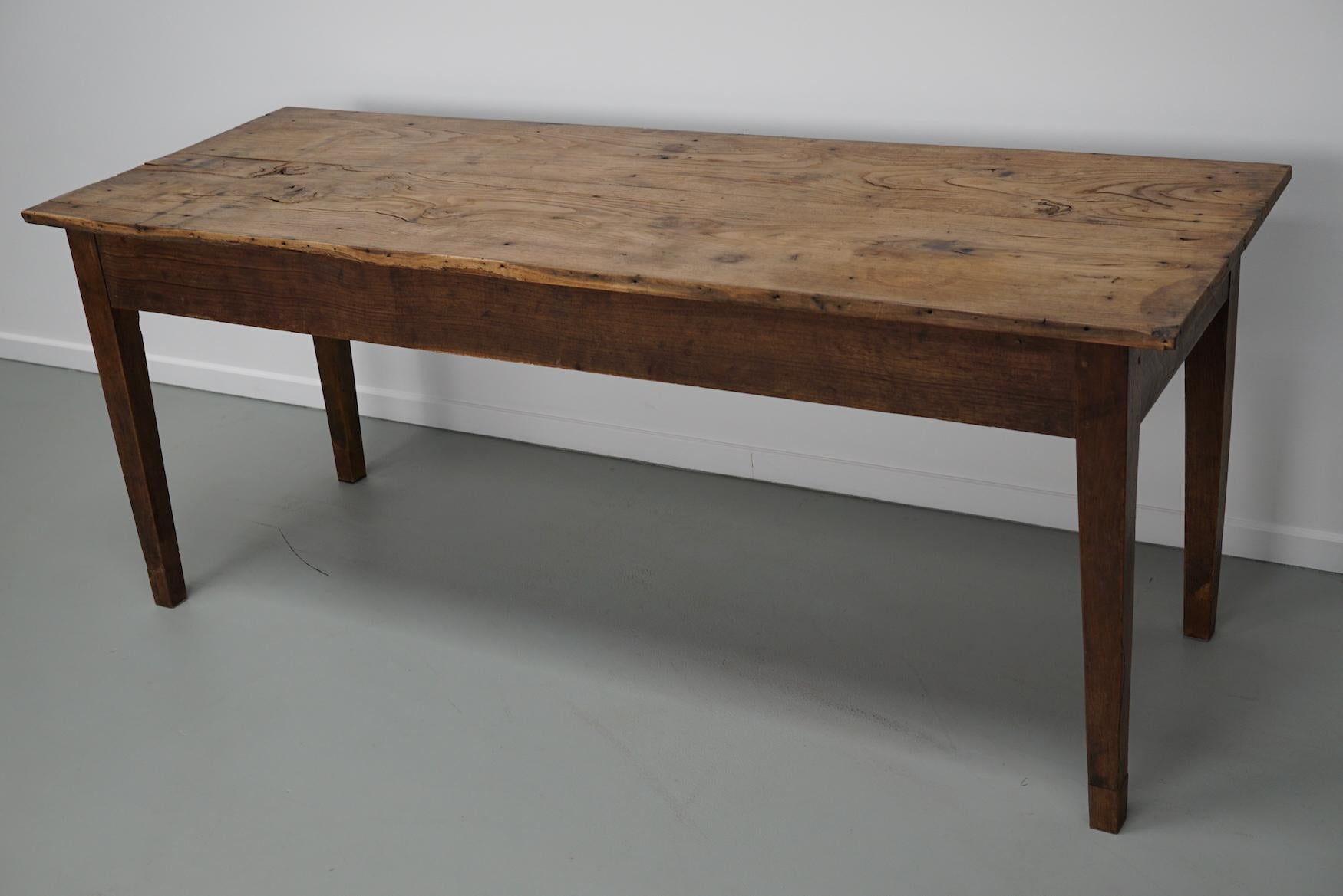 This elegant table was made in France in the early 20th century. The table was made from elm and oak with beautiful grain patterns. It has a very warm but light color and the table shows marks of use and has a great patina. The knee height is 62 cm.