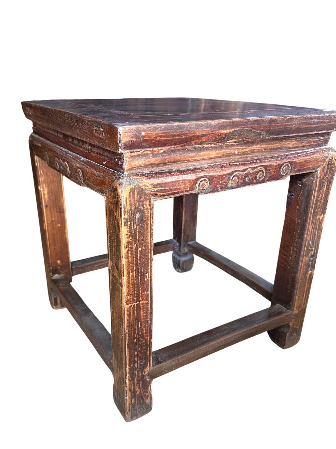 This exquisite Qing Dynasty elm wood stool from circa 1890 epitomizes the artistry and craftsmanship of the era. Handcrafted from premium elm wood, the stool features a square seat with a slightly raised edge, supported by four sturdy legs connected