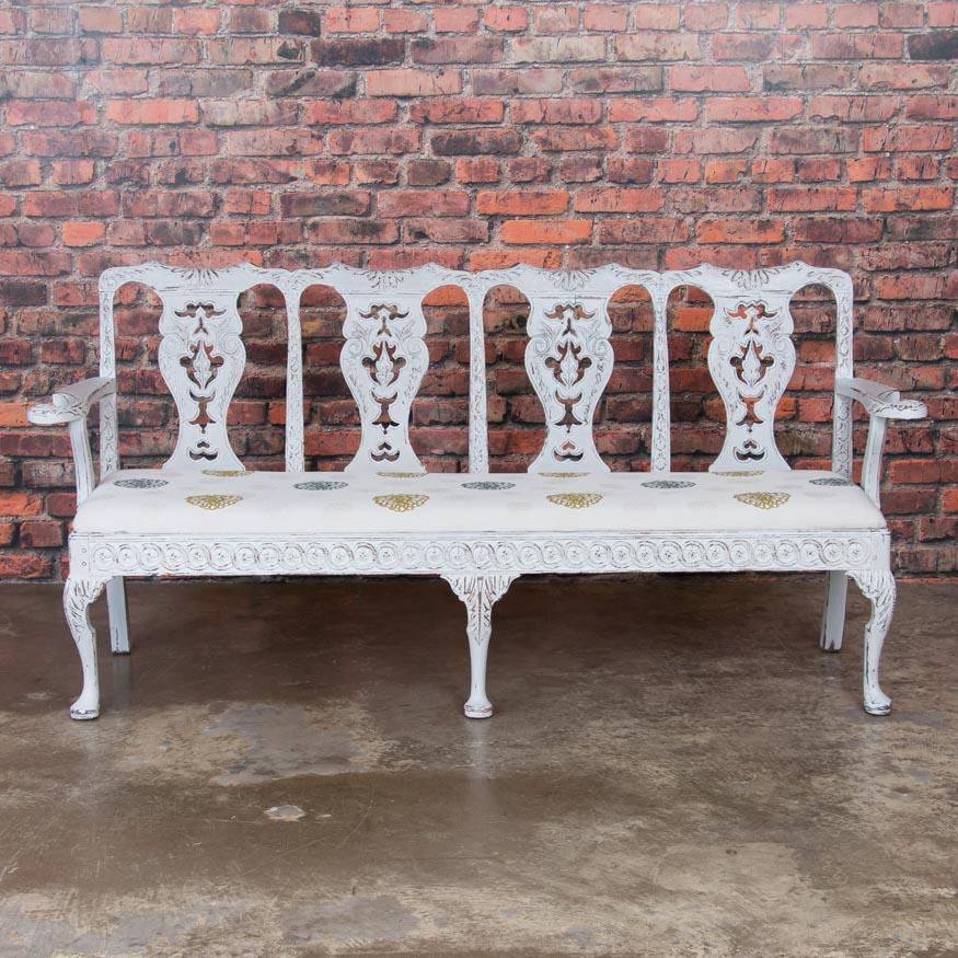 The lovely, soft colors and traditional carving of the Gustavian period are well displayed in this exquisite bench. Where the new light grey painted finish is worn away, the darker natural wood comes through, enhancing the exceptionally carved